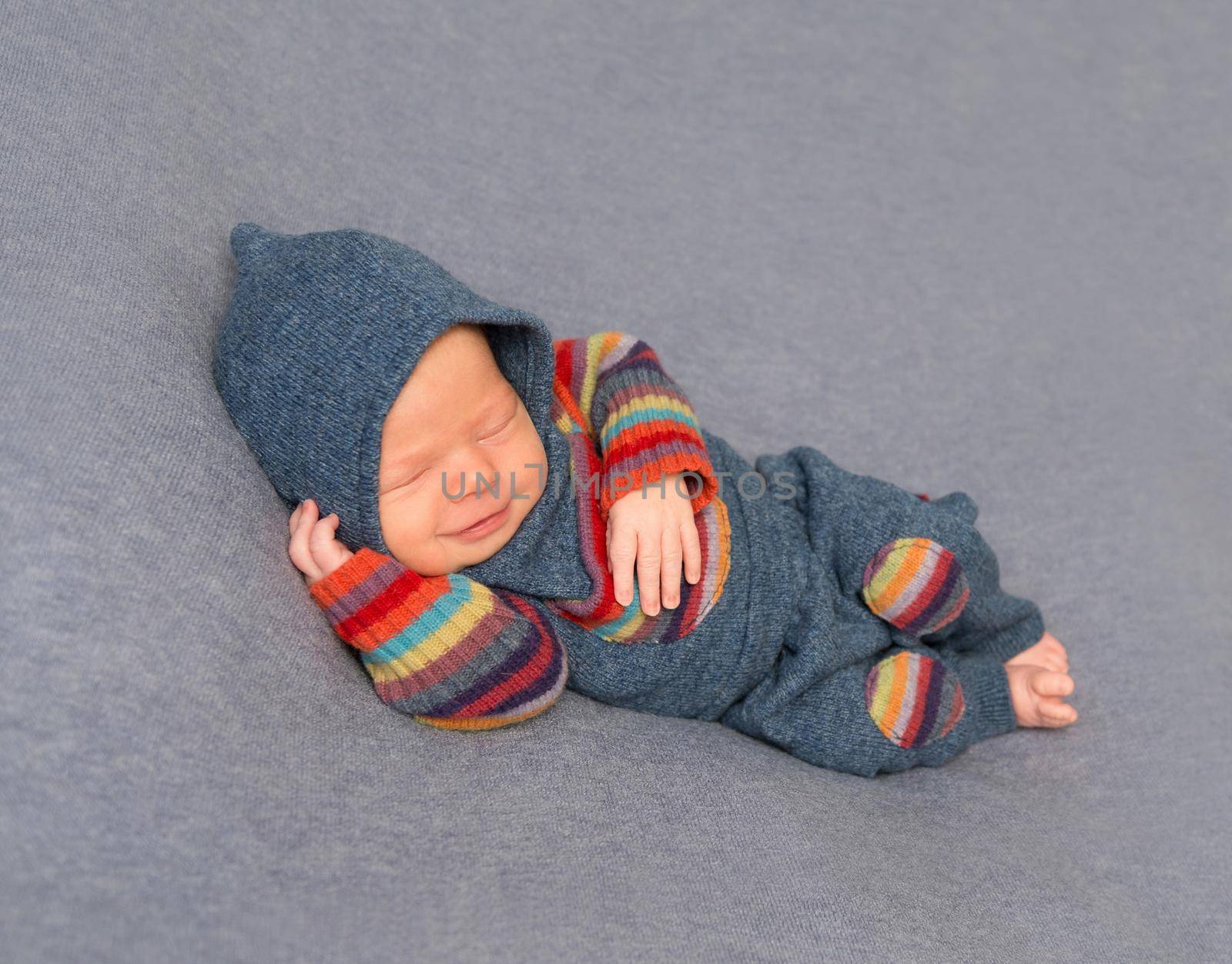 Frowning aborable kid in a bright outfit with his hand under his head, sleeping