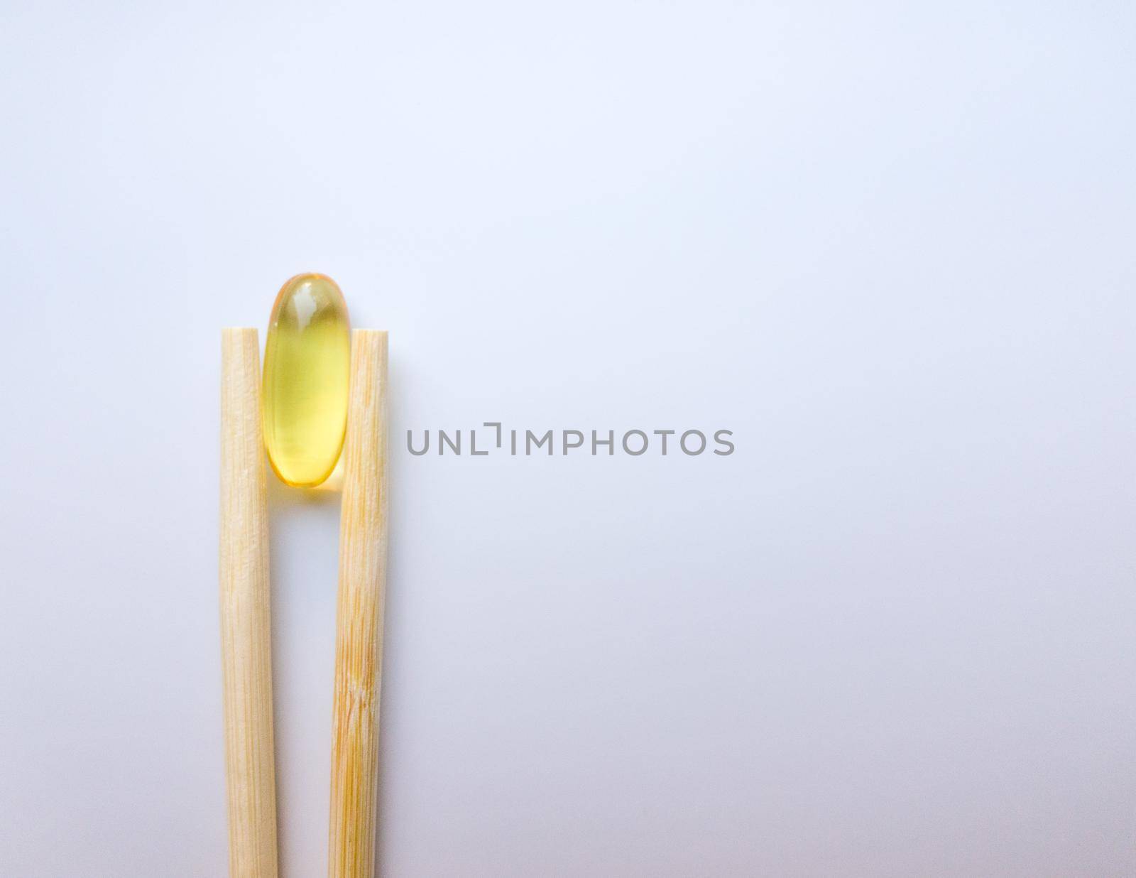 Fish oil capsules with Chinese chopsticks. Omega 3 on a white background. High Resolution Product. Food supplement. Vitamins for a healthy lifestyle. Fatty acid. Metabolism in the body
