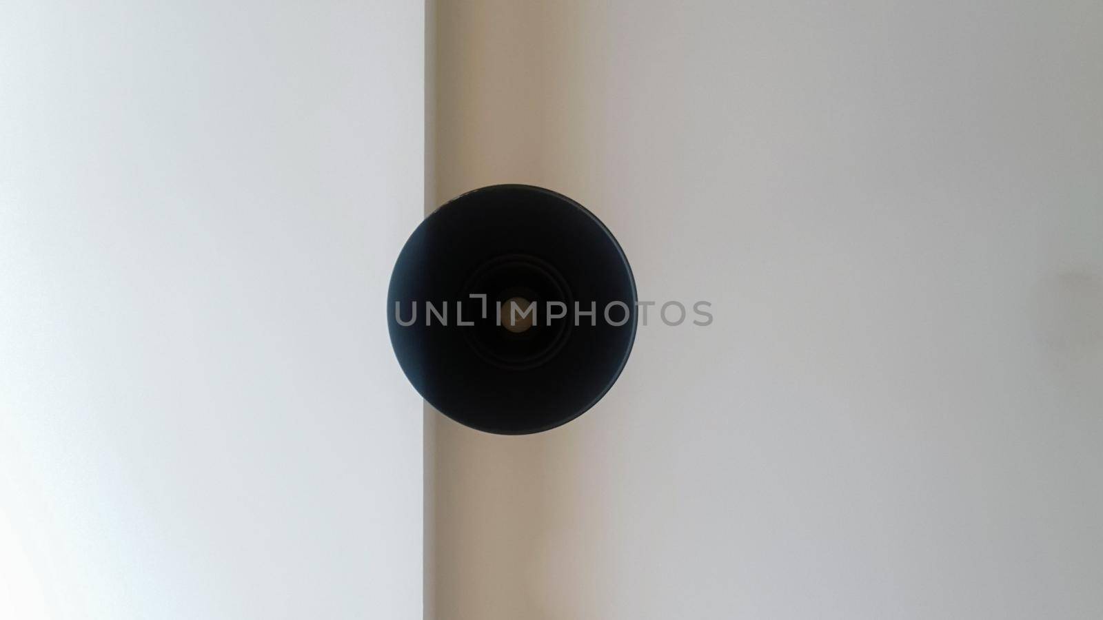 Black round ceiling chandelier or lamp hanging on white from the ceiling. Bottom view of a light bulb. Architectural decoration on the ceiling, hanging round chandelier. Minimalism.