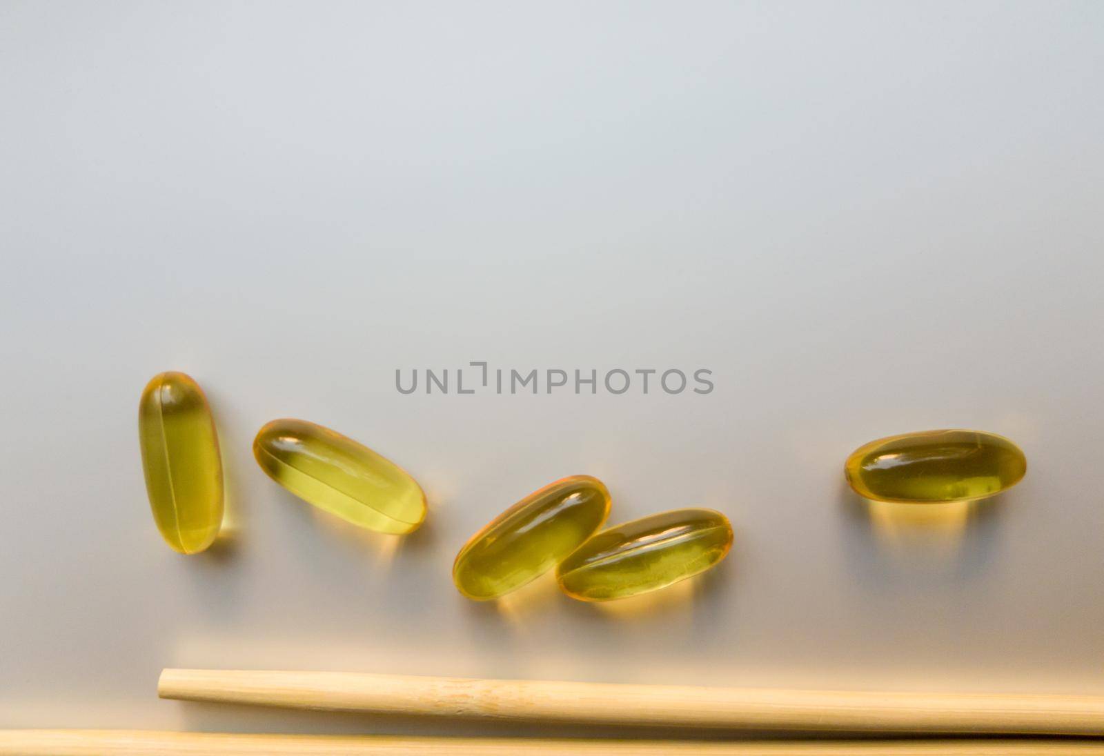 Fish oil capsules with Chinese chopsticks. Omega 3 on a white background. High Resolution Product. Food supplement. Vitamins for a healthy lifestyle. Fatty acid. Metabolism in the body