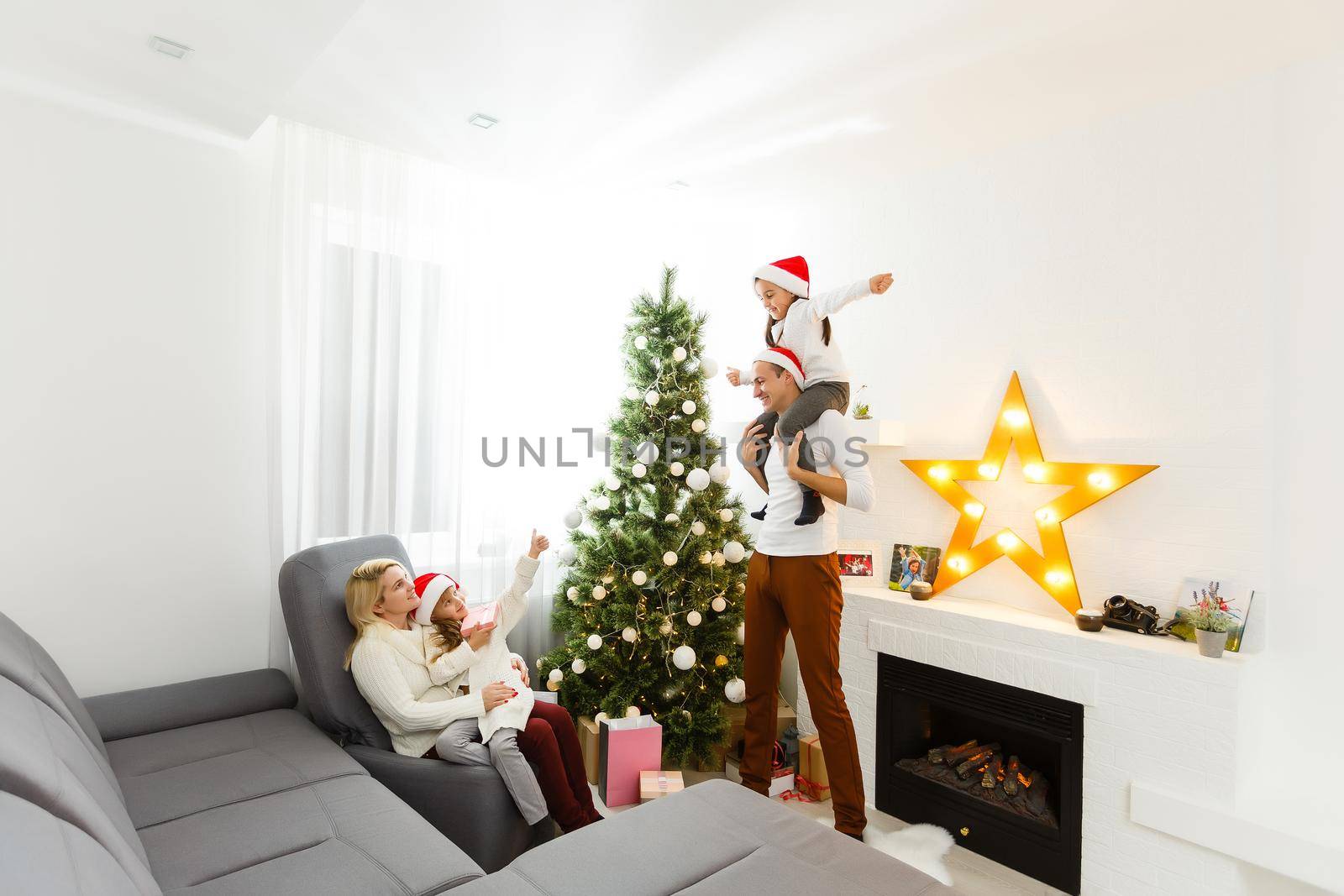 happy family father mother and children sitting by fireplace on Christmas Eve by Andelov13