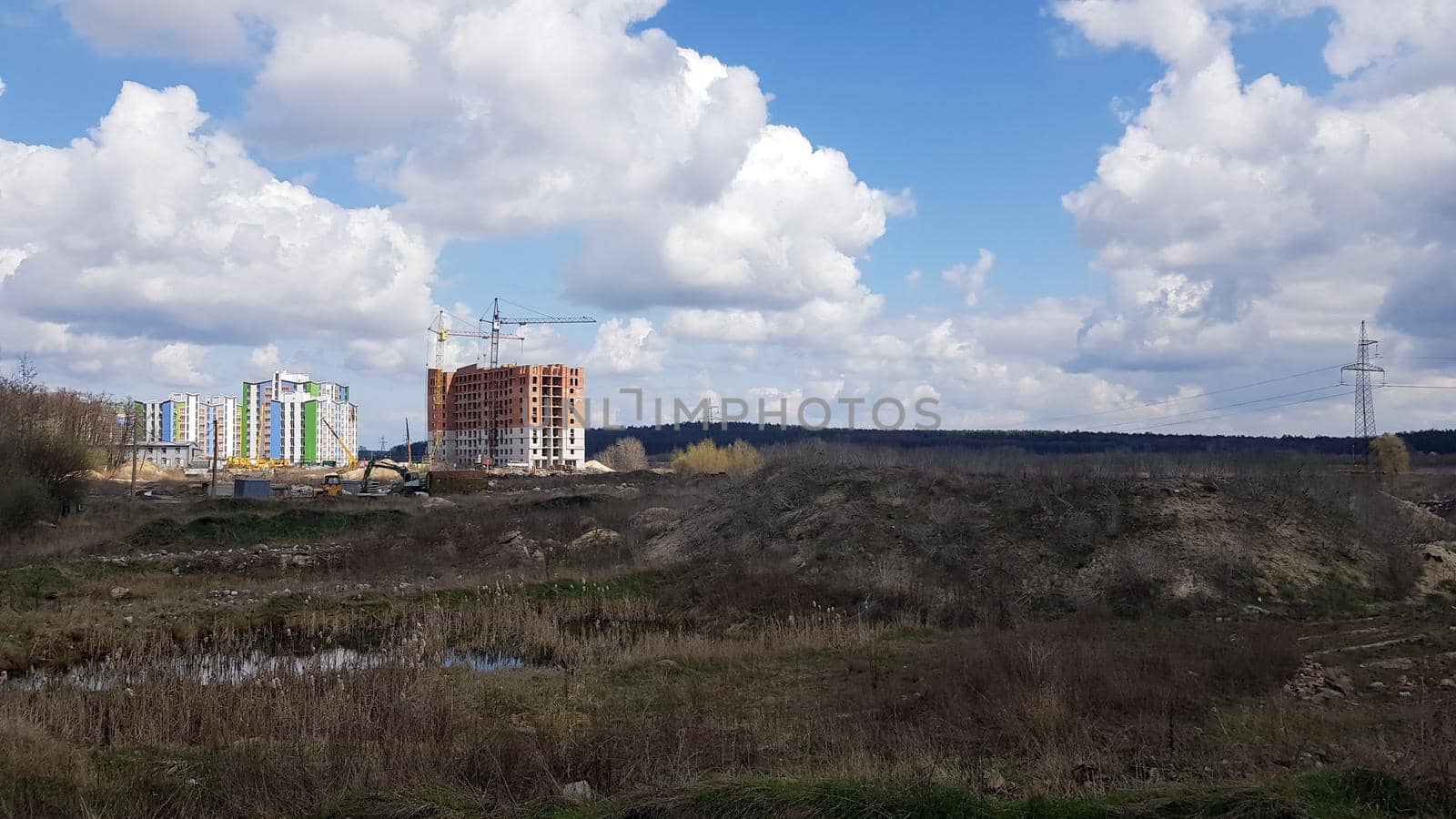 A snapshot of the field and the construction of multi-apartment high-rise residential buildings that began there on a sunny day. Construction work of a new residential area