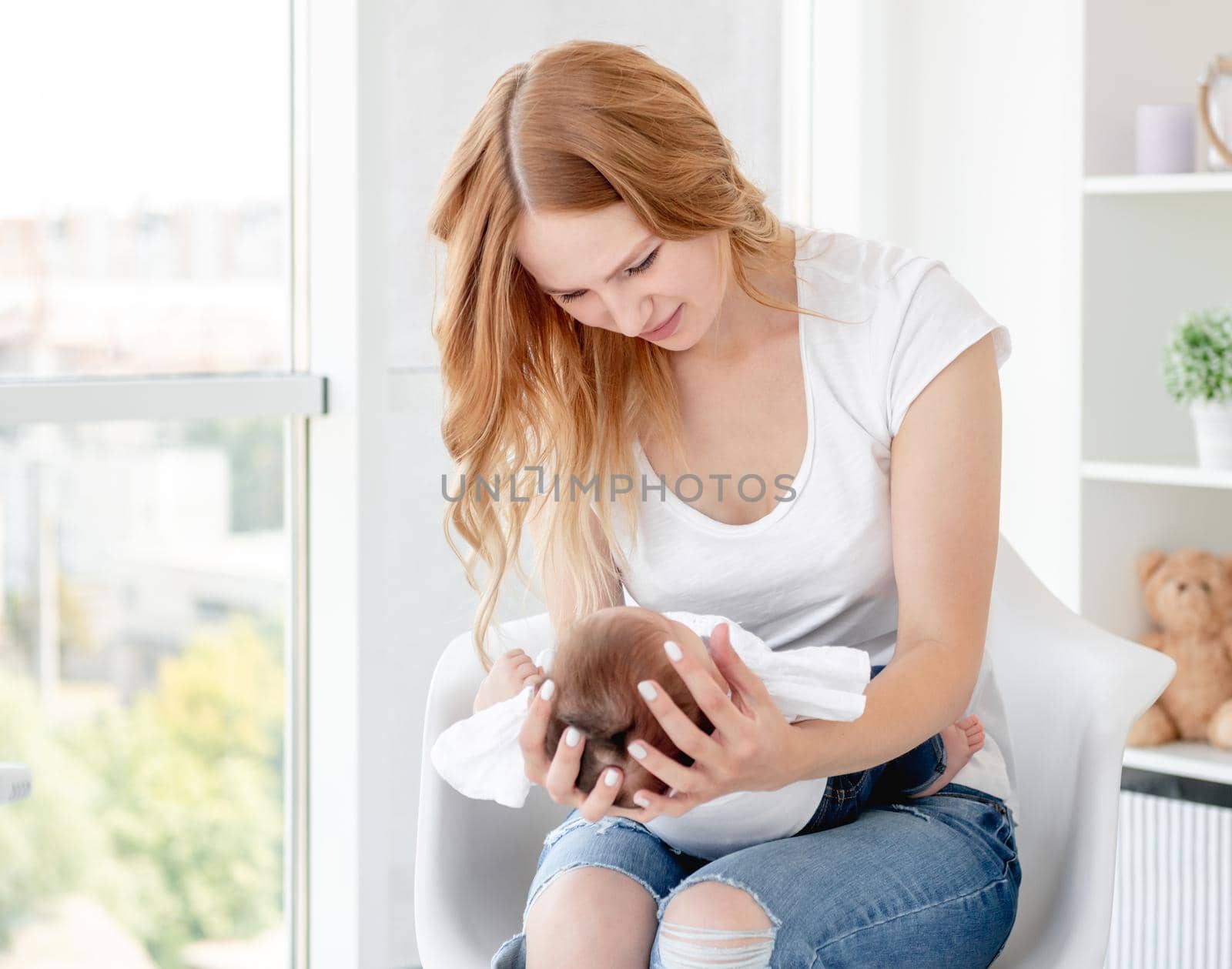 Mother holding her child sitting on chair in light room