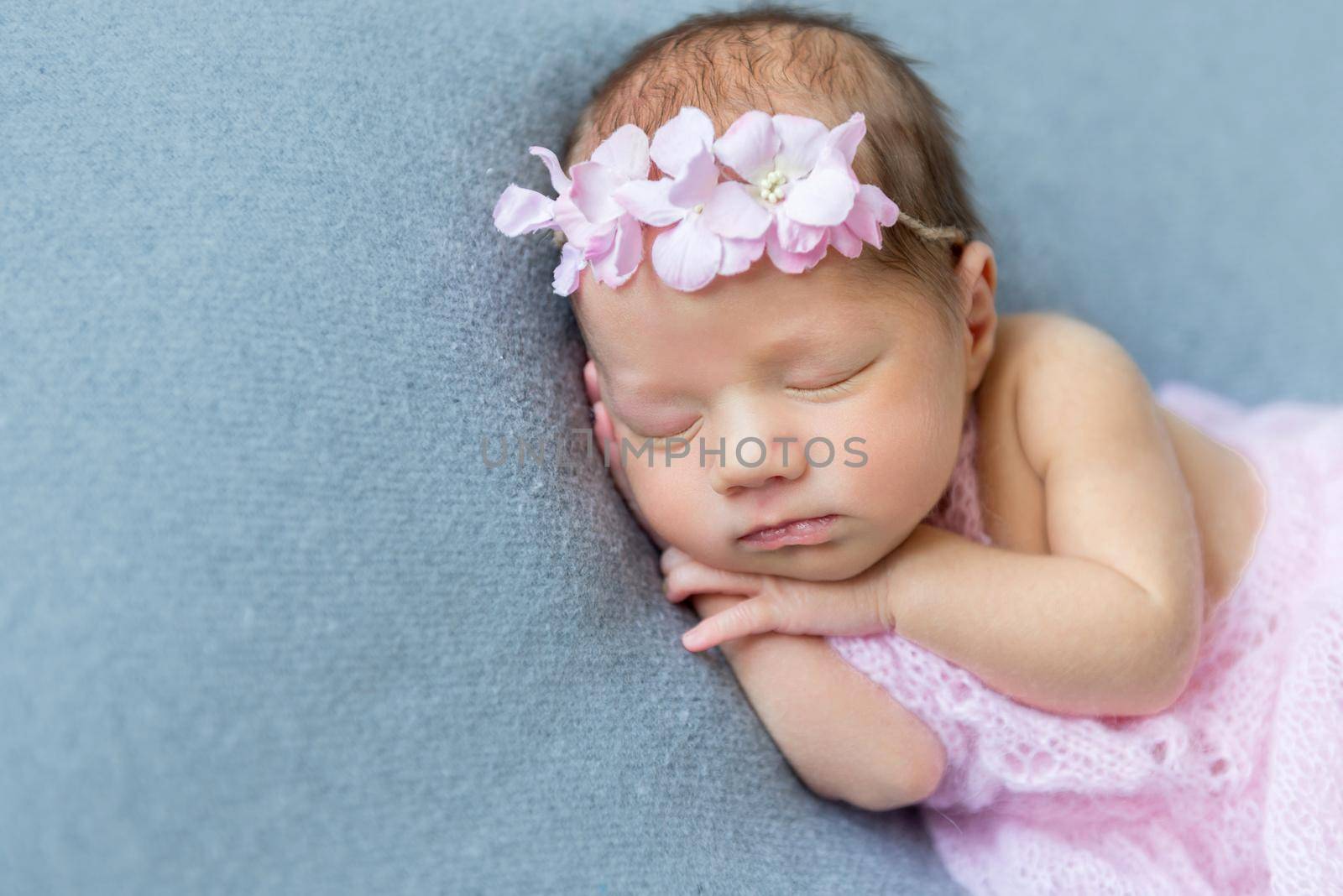 Adorable little girl napping on her side, dressed in a sweet pink dress, closeup
