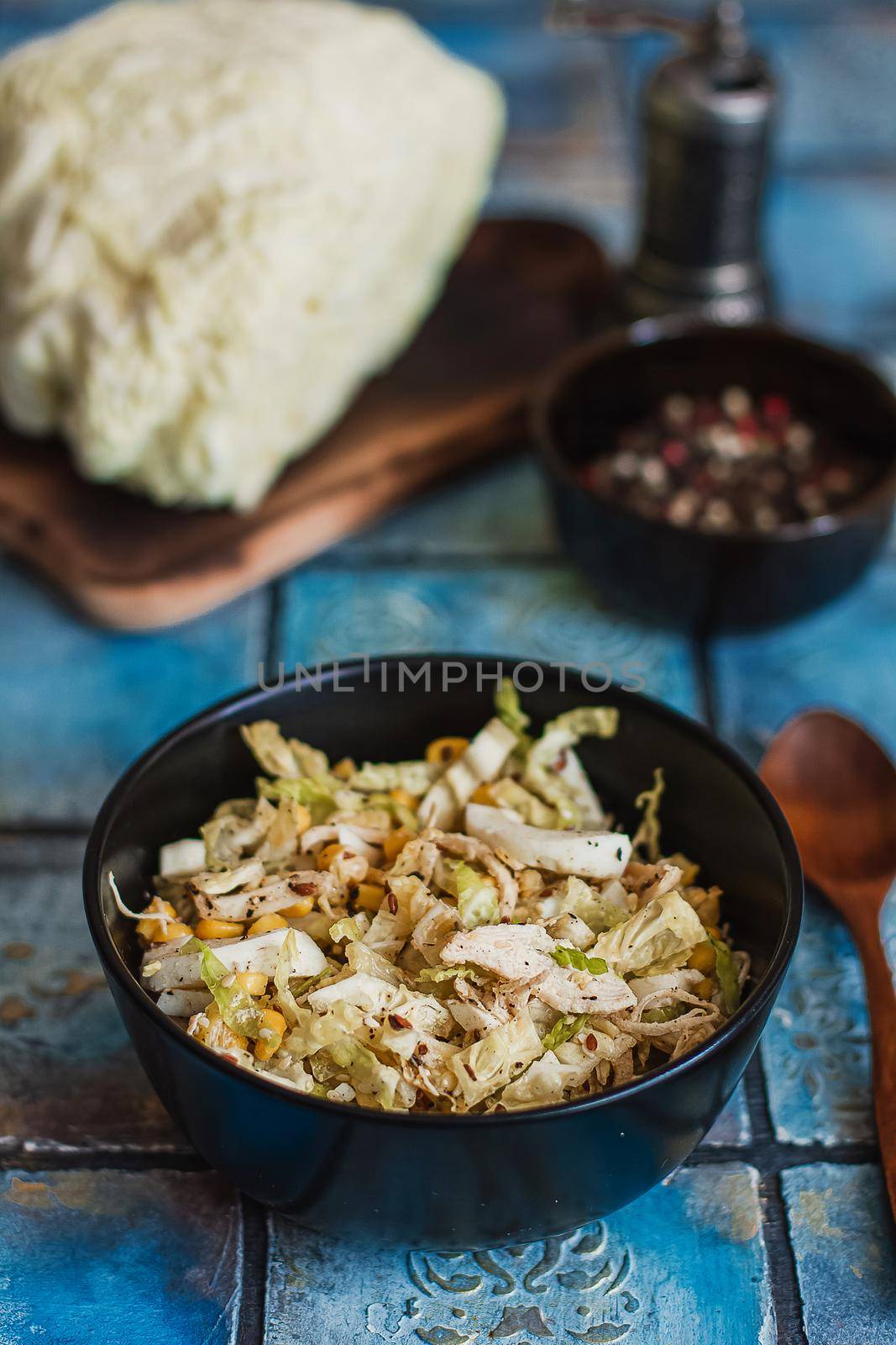 Salad with cabbage, eggs, corns and meat on the plate on rustic tiled table.