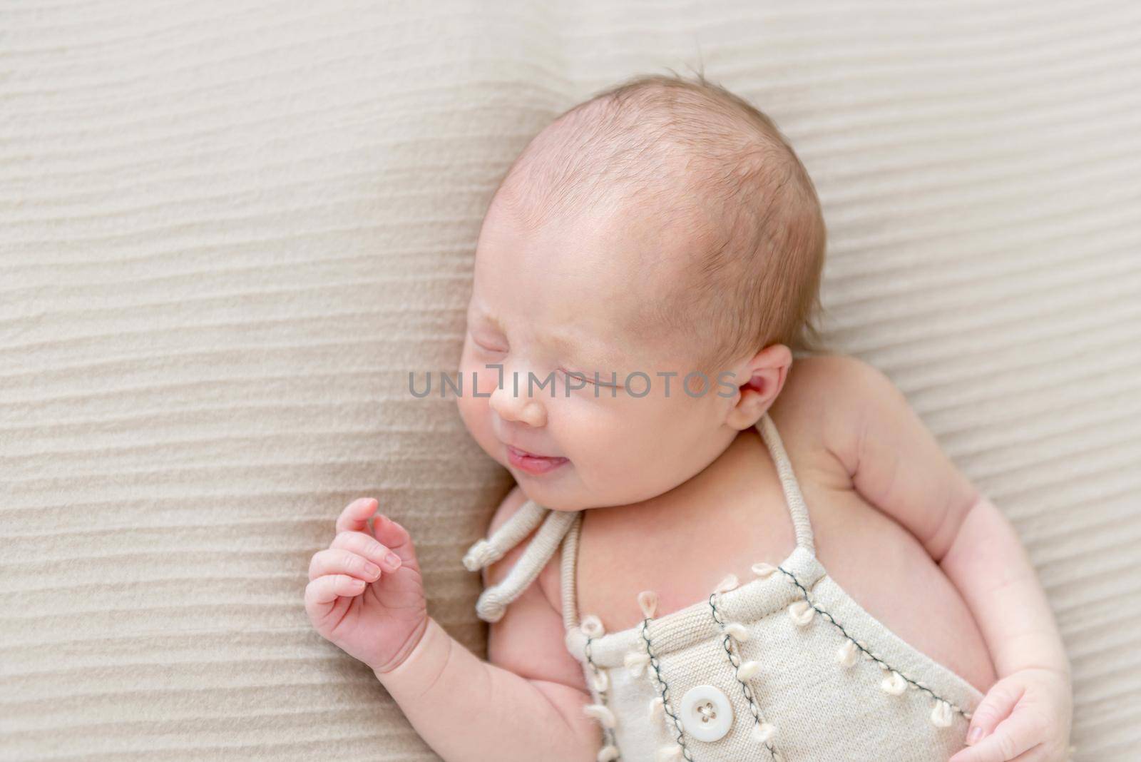 Lovely emotions of an infant in pastel colored costume sleeping on a soft blanket, closeup