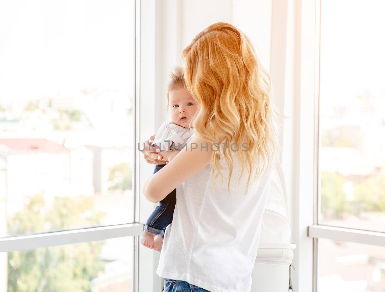 Young mother hugging cute baby at home
