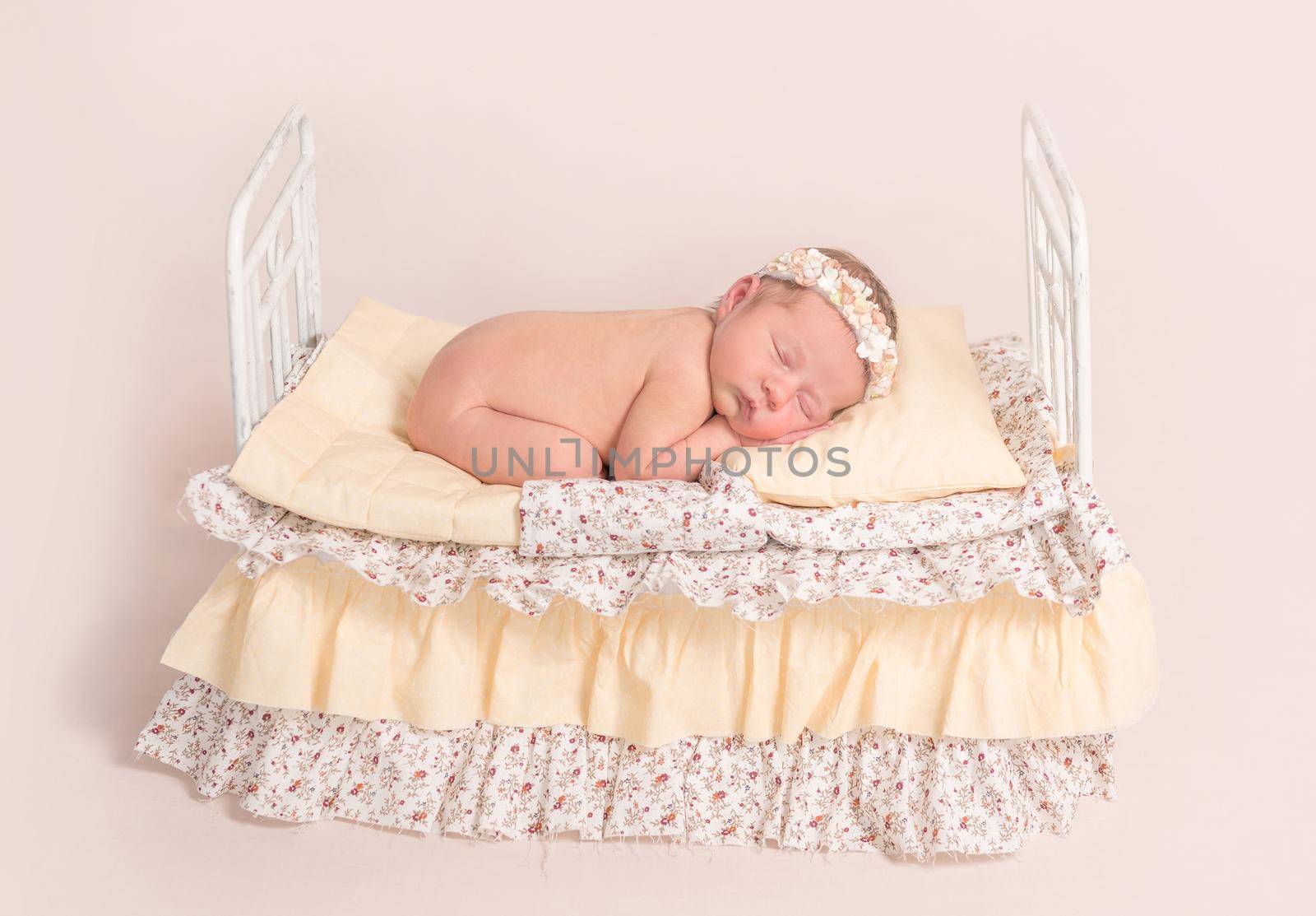 infant sleeping on adult like bed with yellow sheets and covers, on top of it