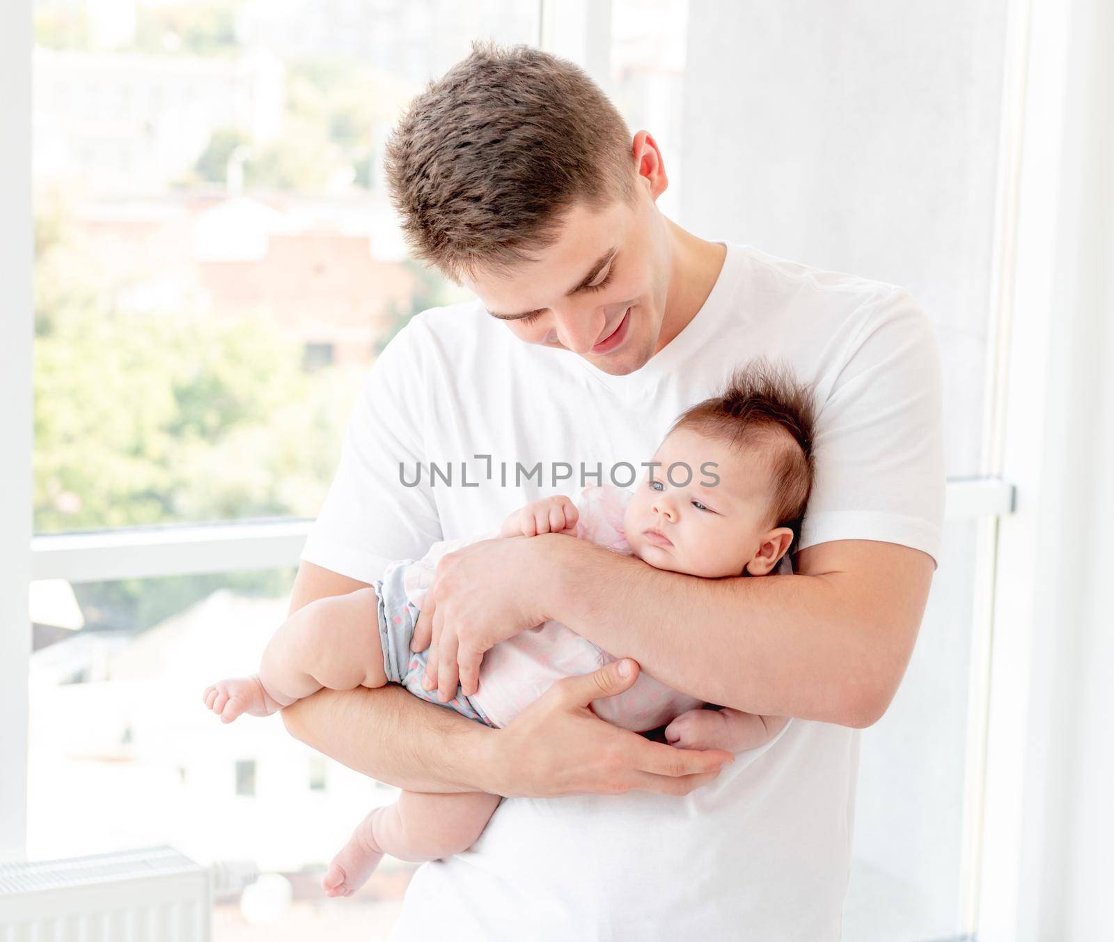 Father embracing infant near window