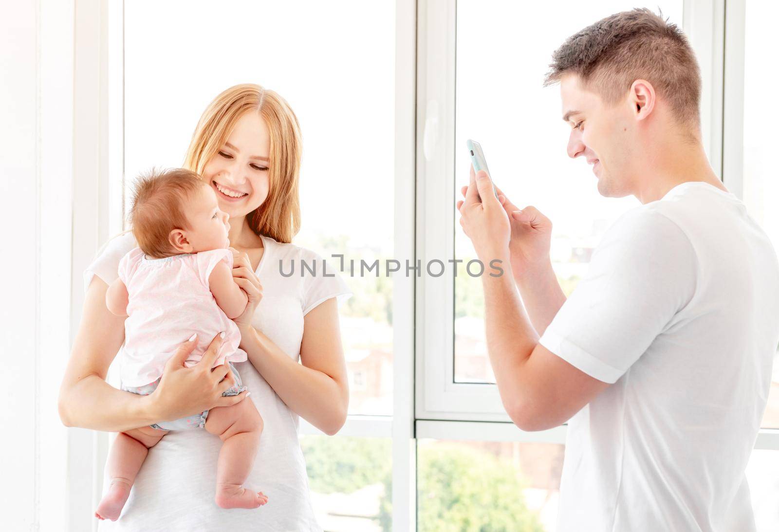 Mother and baby posing for father taking photo indoors