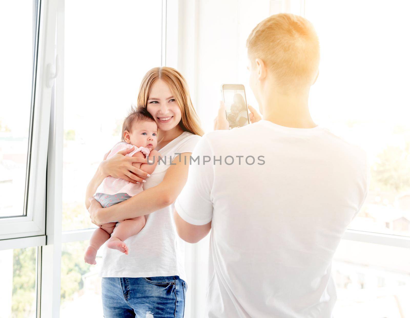 Mother and baby posing for father taking photo indoors