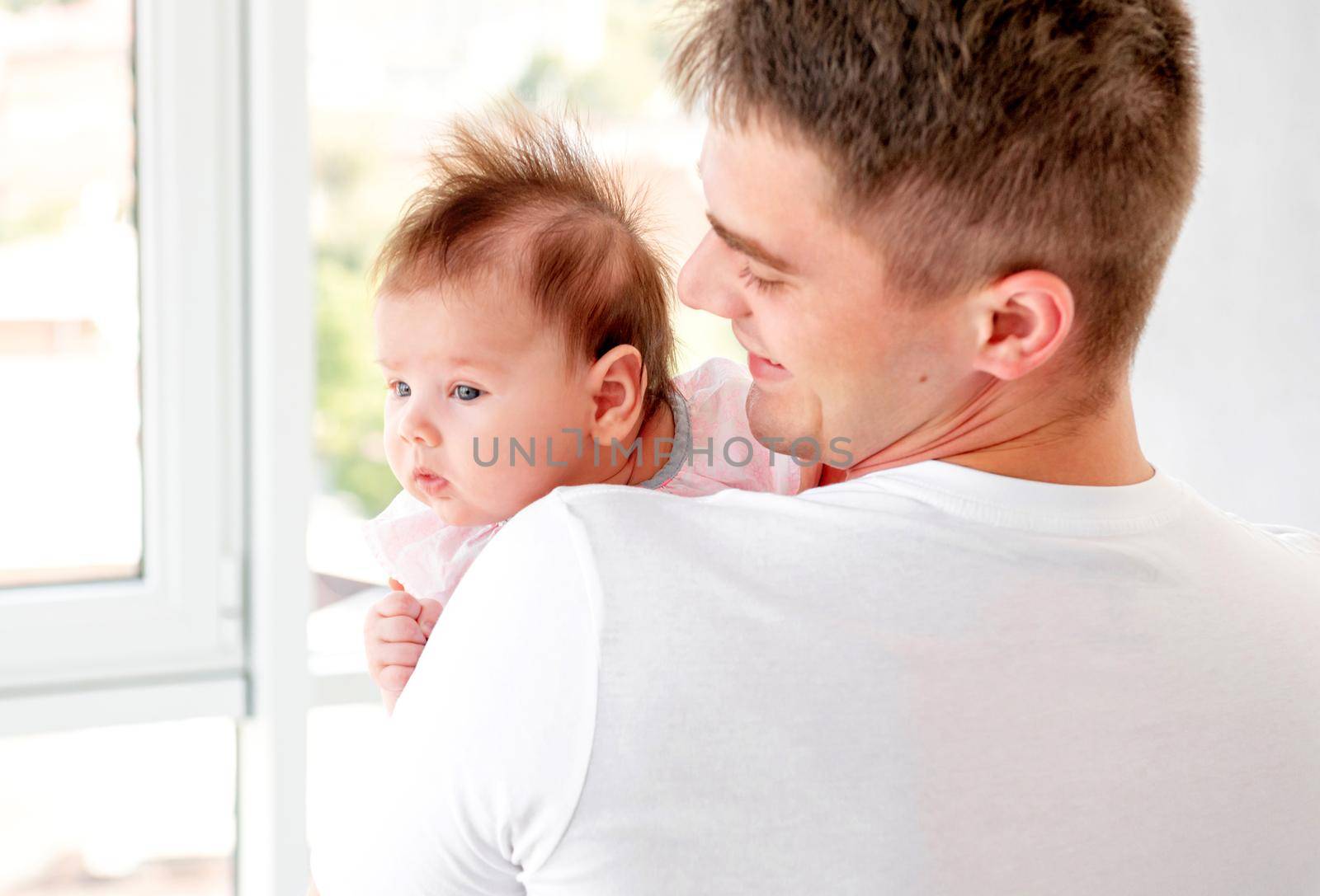 Father embracing infant near window