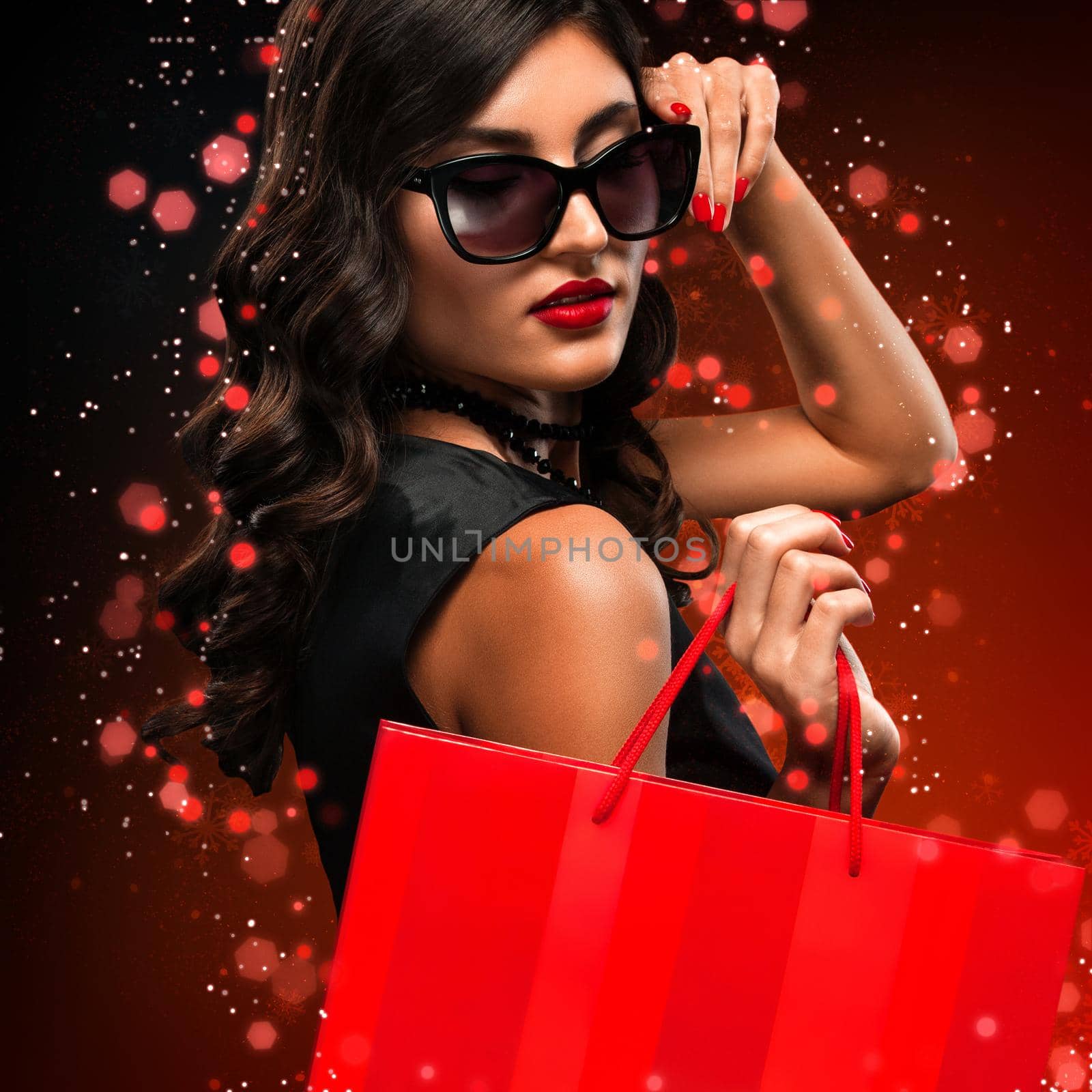 Christmas and Black friday sale concept. Shopping woman holding red bag isolated on dark background in holiday by MikeOrlov