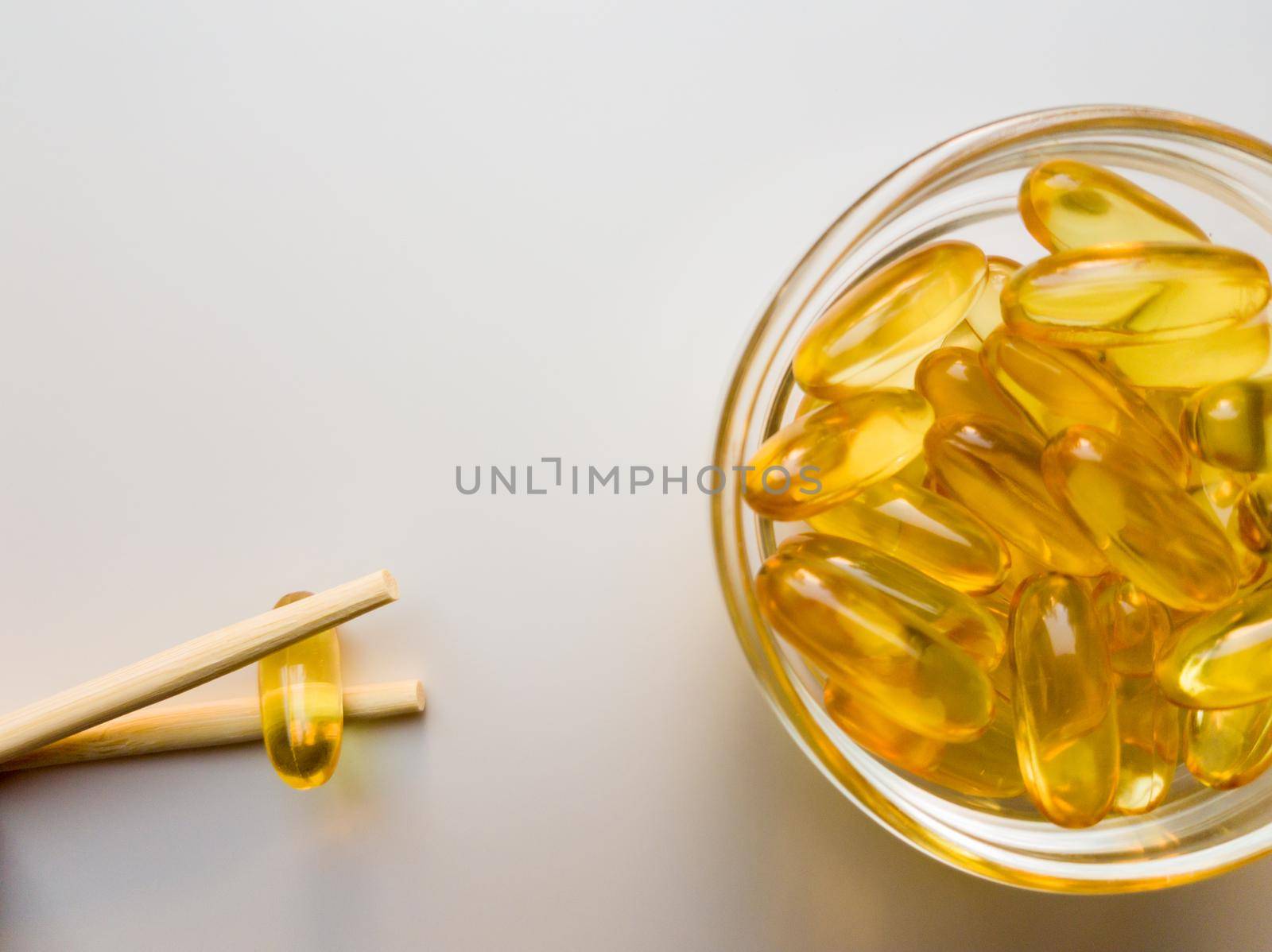Fish oil capsules on a saucer with chopsticks. Bunch of vitamin omega 3 pills on a white background. Close-up, top view, high resolution product. Metabolism in the body. Body calcium