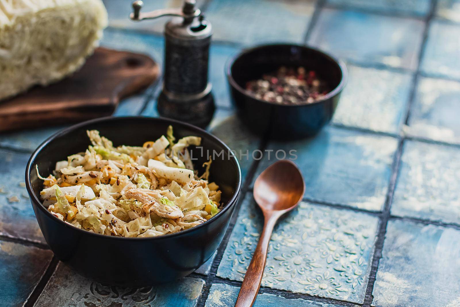 Salad with cabbage, eggs, corns and meat on the plate on rustic tiled table.
