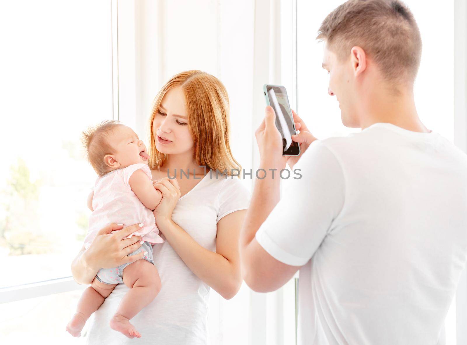 Mother and baby posing for father taking photo indoors