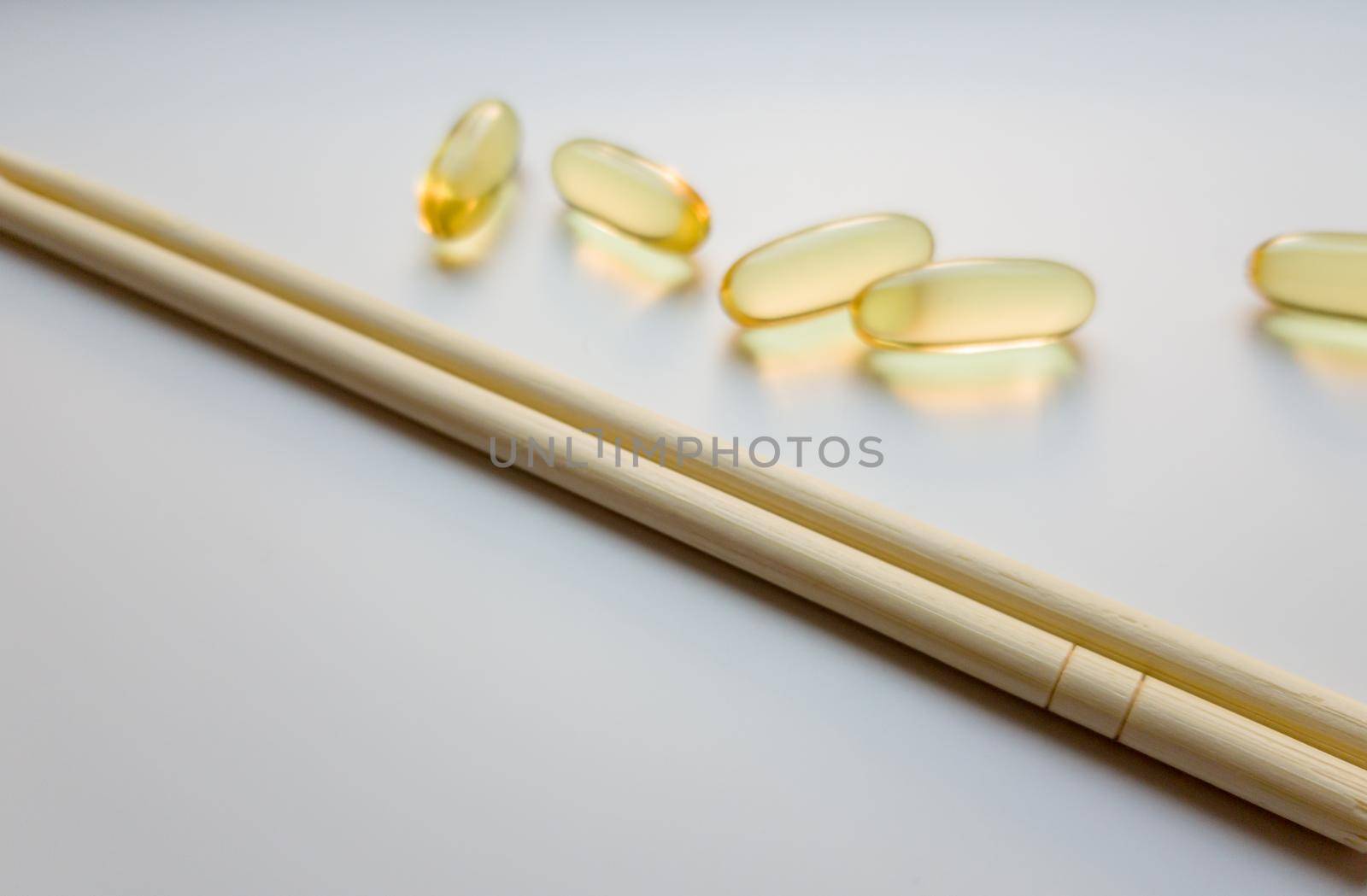 Fish oil capsules with Chinese chopsticks. Omega 3 on a white background. High Resolution Product. Food supplement. Vitamins for a healthy lifestyle. Fatty acid. Metabolism in the body