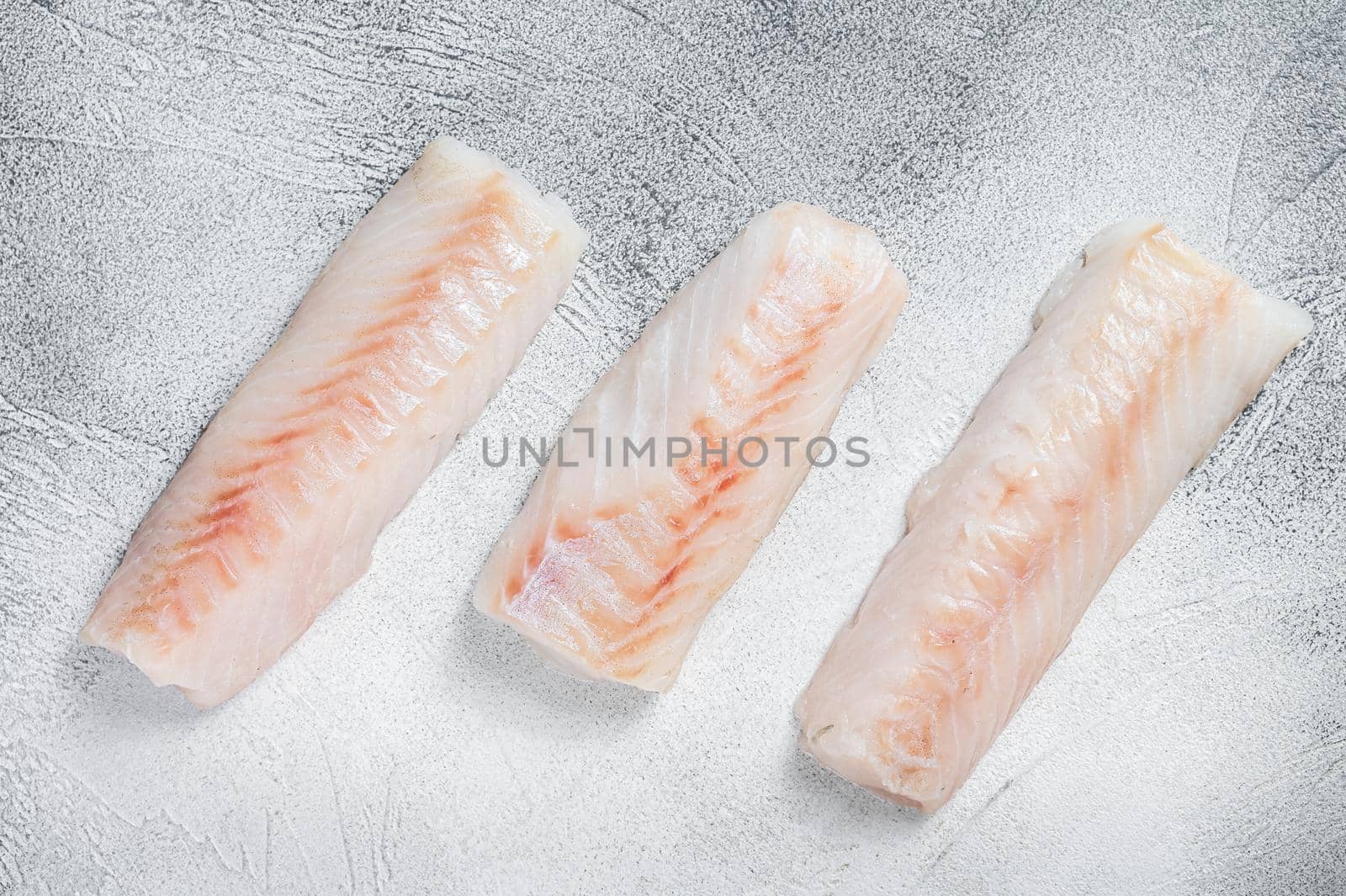 Raw Norwegian cod fish fillet on kitchen table. White background. Top view.