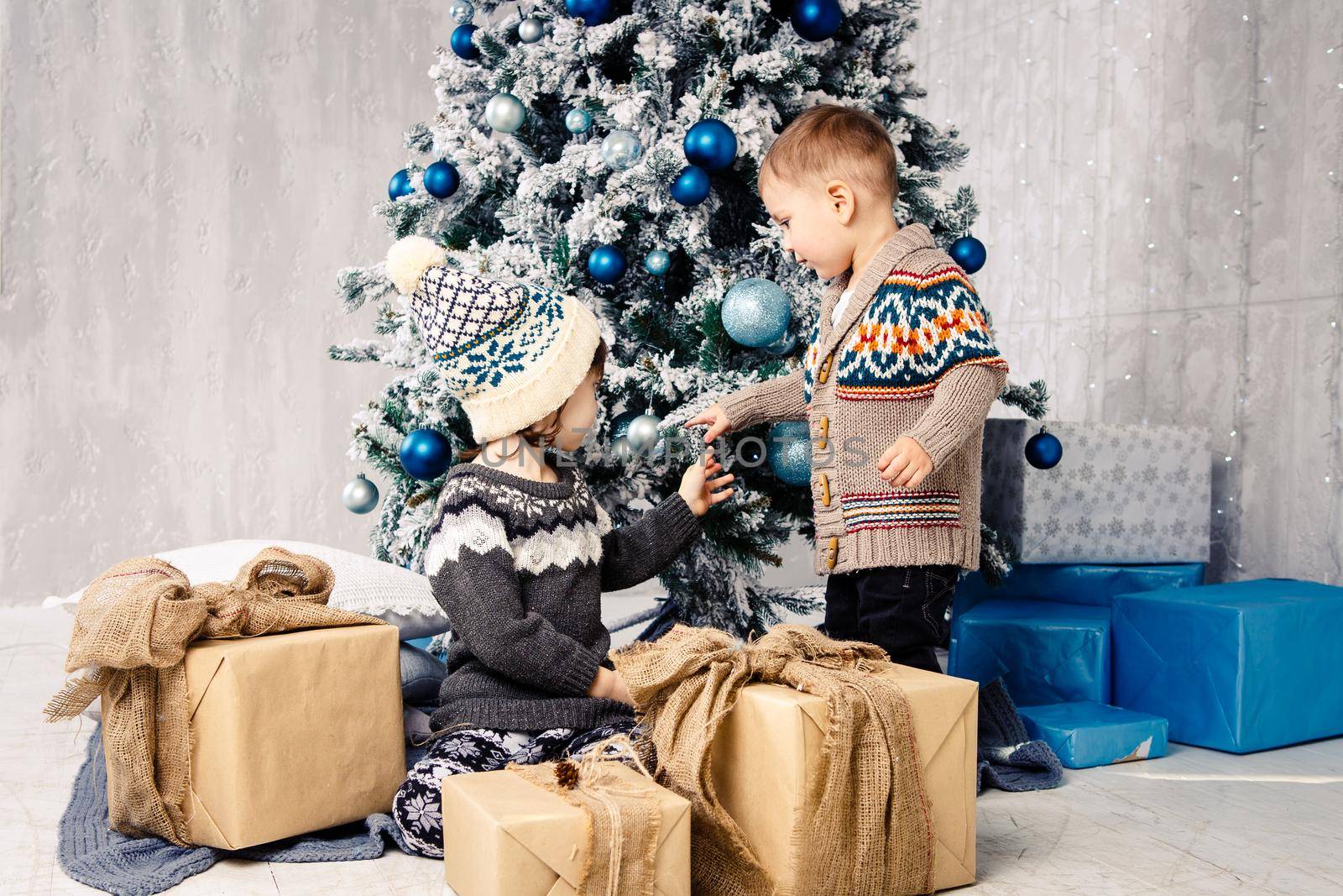 Brother and sister with gift boxes. Sitting under the Christmas tree. brother and sister are having fun opening presents under the Christmas tree. Children with Christmas presents by Tomashevska