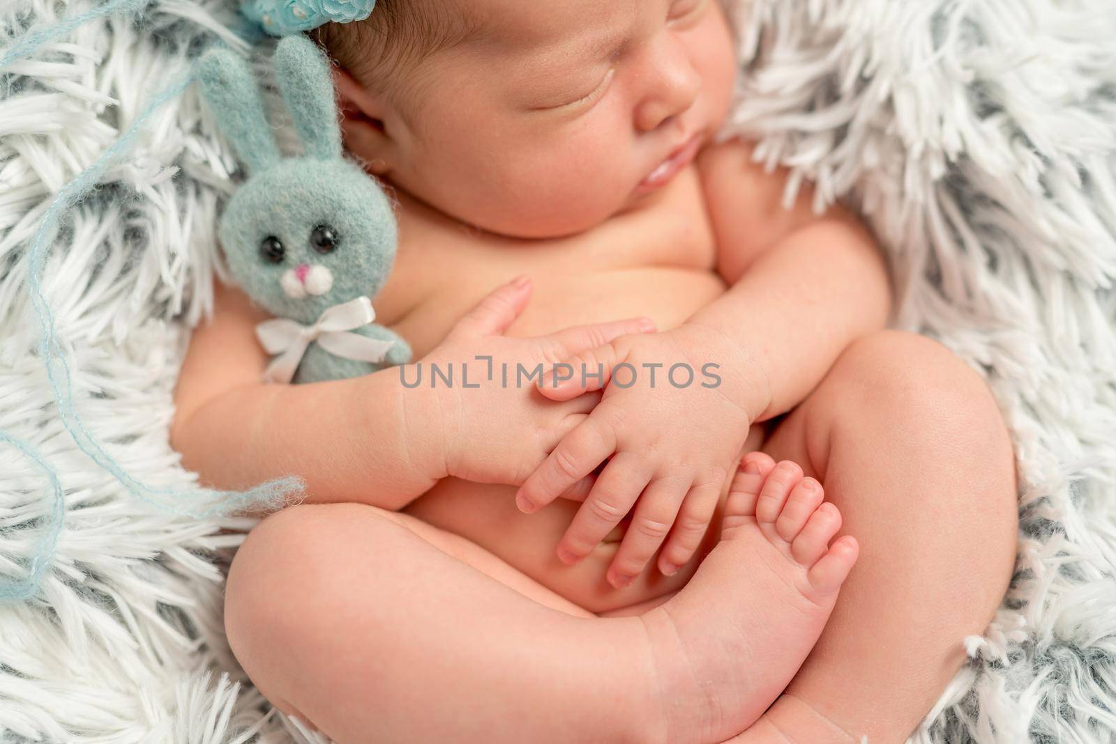 funny sleepy newborn baby holding little grey toy, closeup, top view