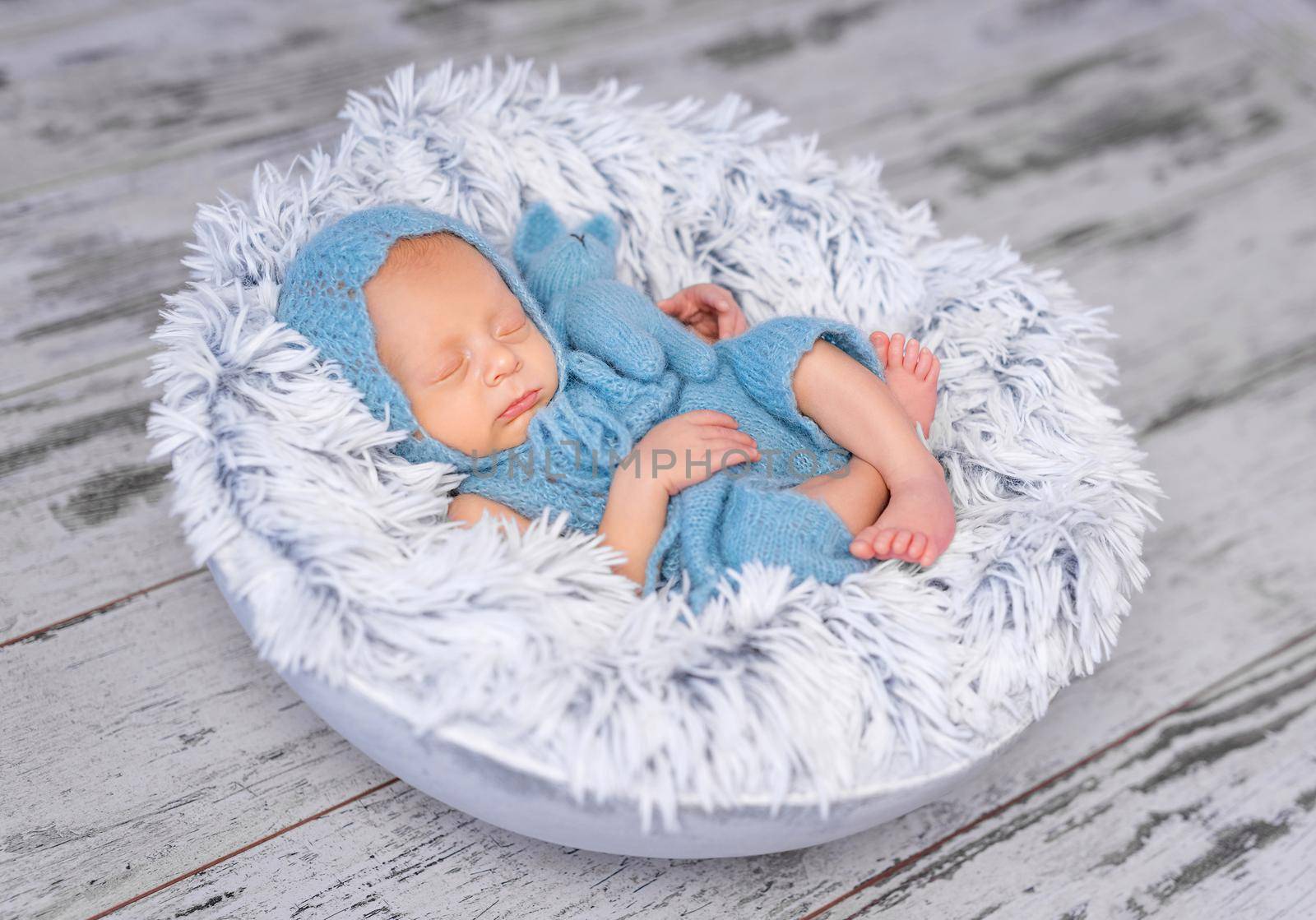 lovely infant in hat and jumpsuit sleeping on round bed by tan4ikk1