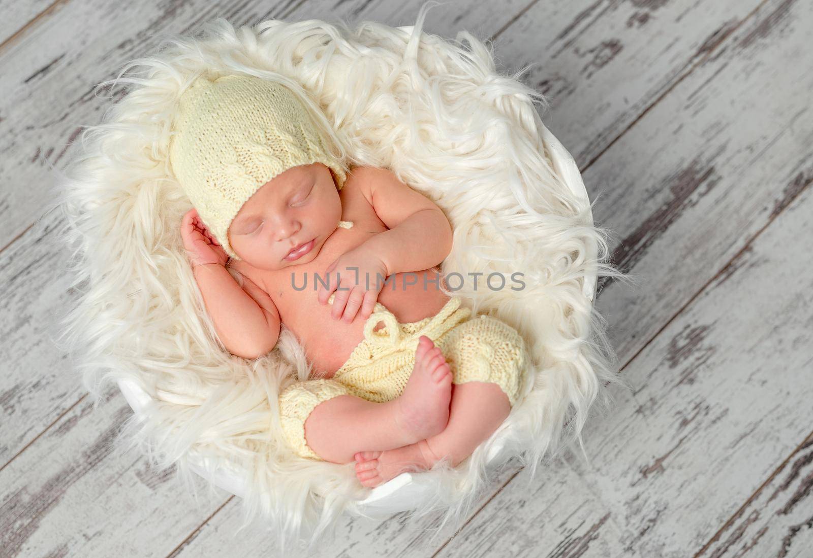 sweet newborn baby in hat and panties sleeping on round bed, top view