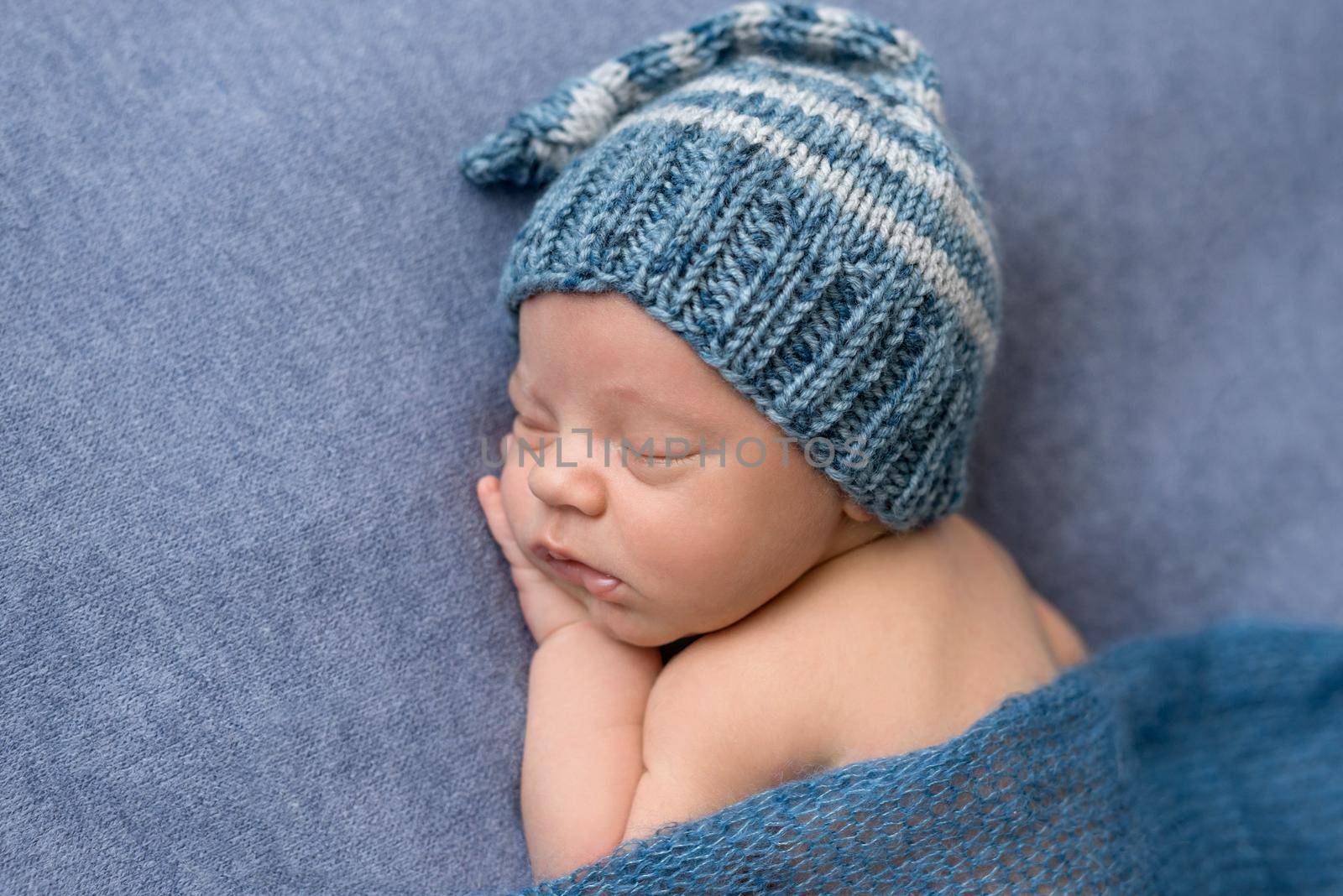 portrait of sweet sleeping newborn baby in hat covered with blanket