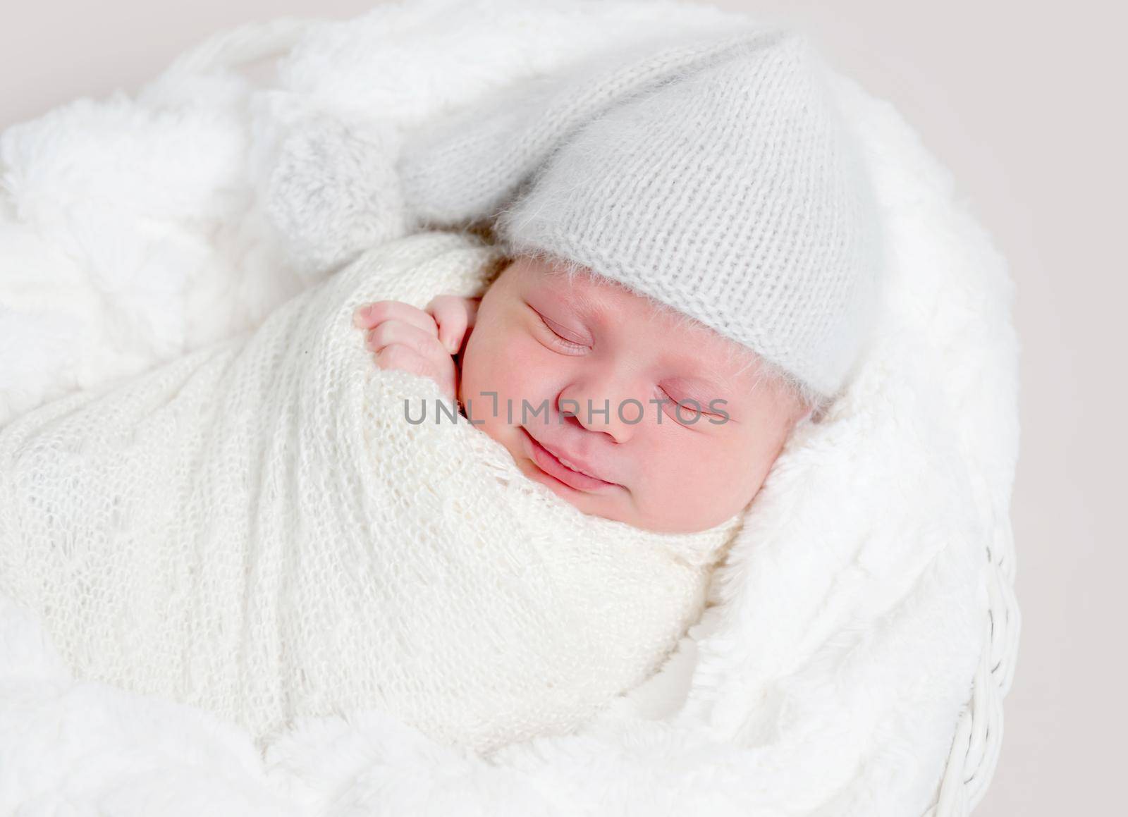 Newborn baby in white wrap laying on basket by tan4ikk1