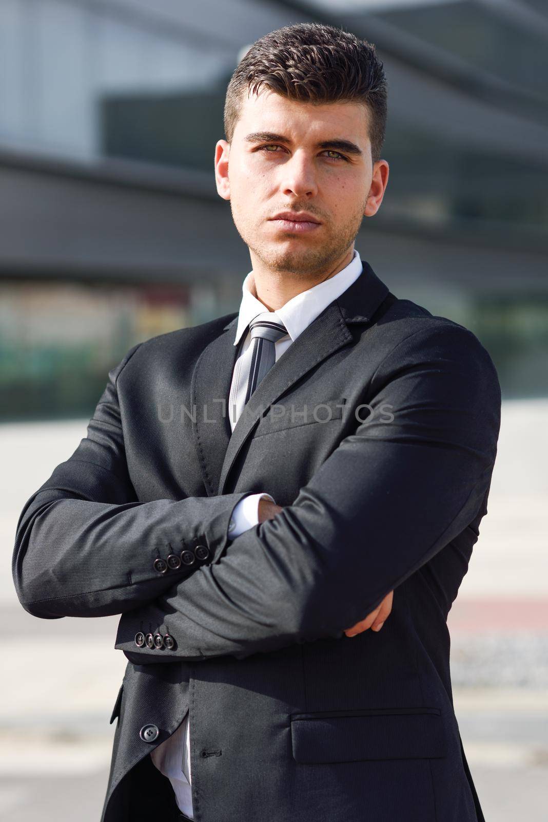 Young businessman near a office building wearing black suit by javiindy