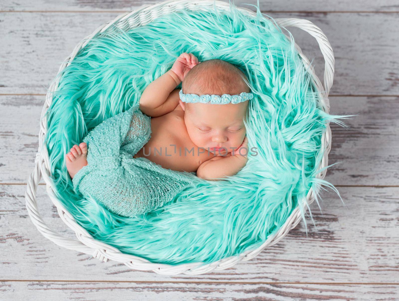 lovely sleeping newborn girl in round cot with turquoise fluffy blanket