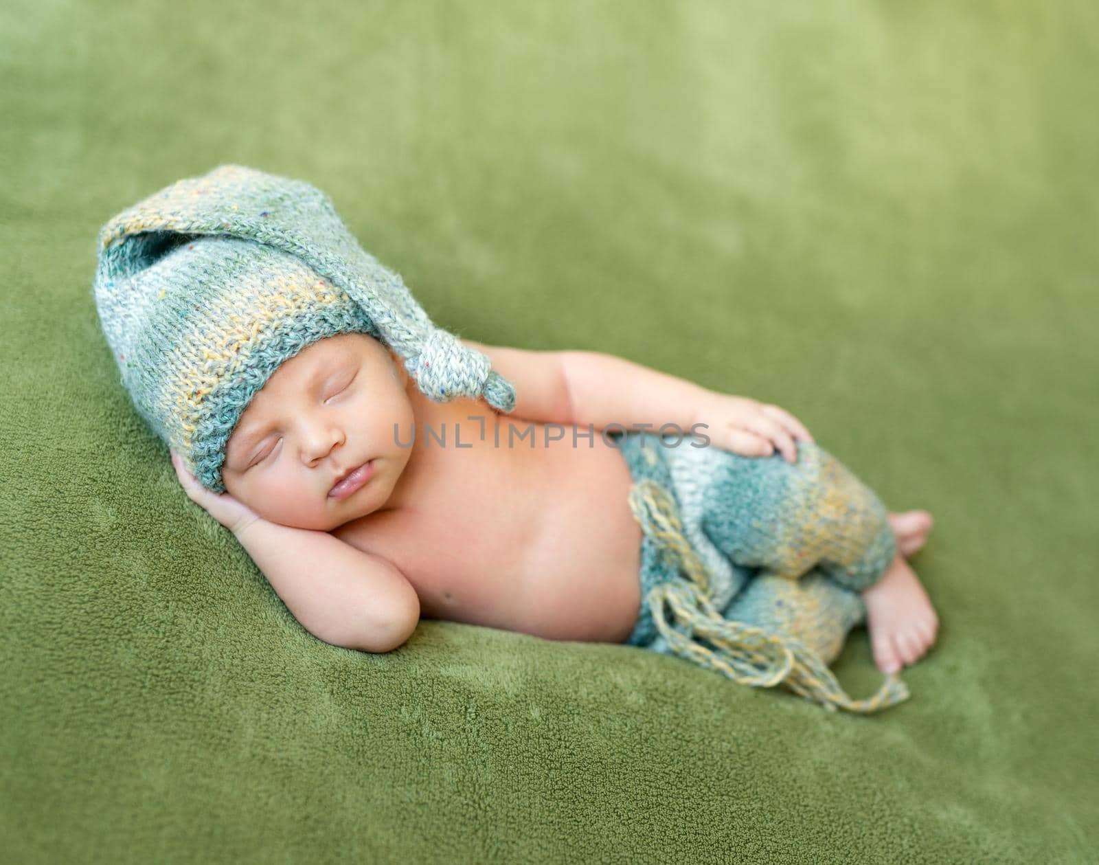 lovely newborn baby in knitted hat and panties sleeps curled up, top view
