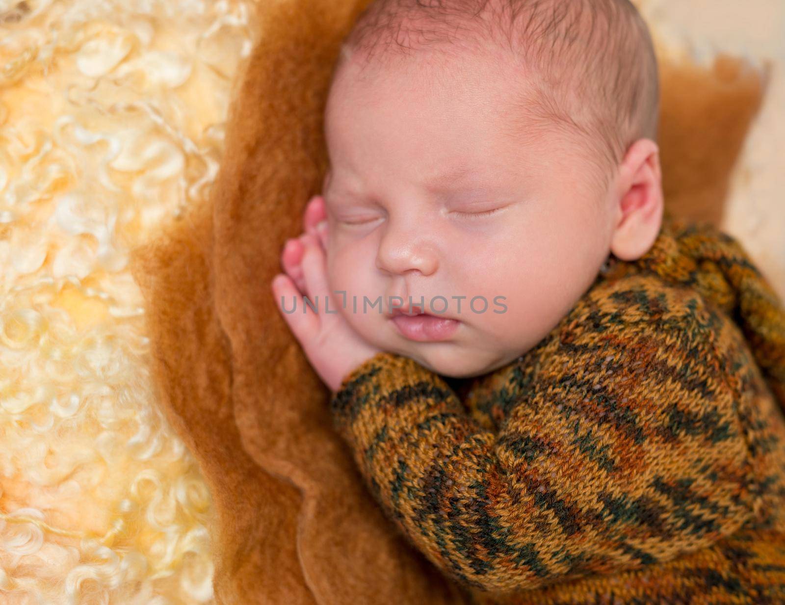 asleep funny baby boy in brown suit with hands under his head and lovely lips