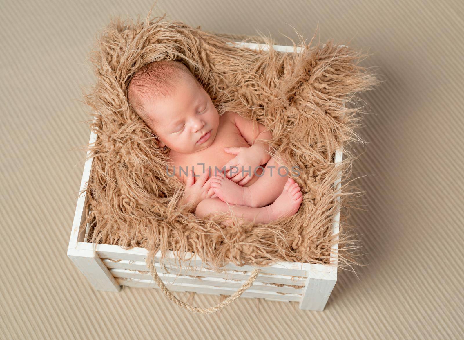 lovely bare sleeping newborn baby in wooden box with fluffy blanket