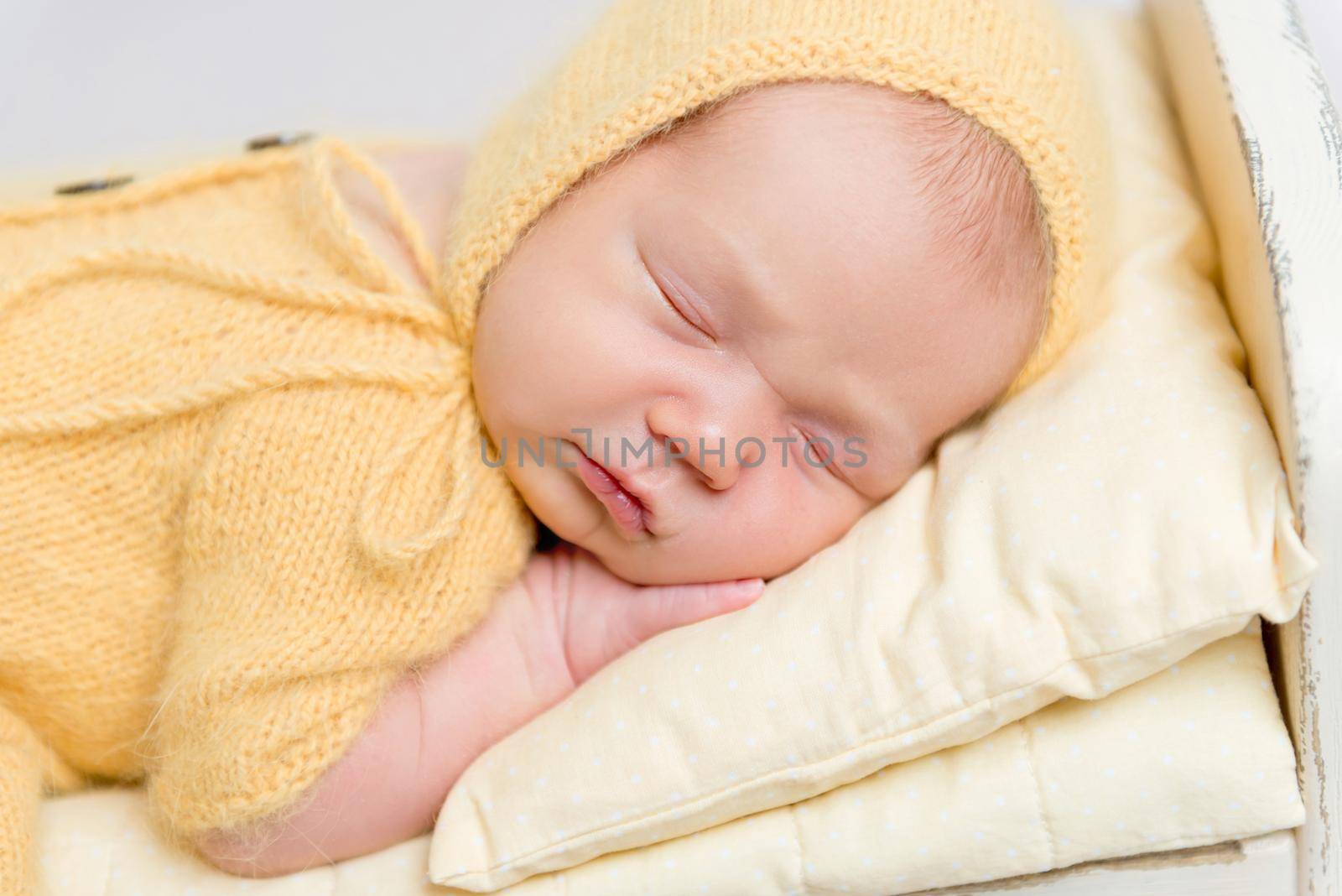 Baby dressed in knitted yellow costume sleeping on crib by tan4ikk1