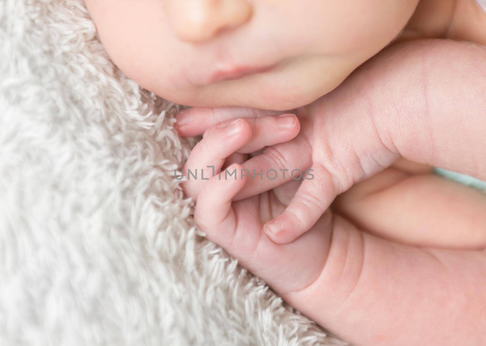 Close-up of newborn tiny hands. Child hands close-up. Little baby hands on white blanket
