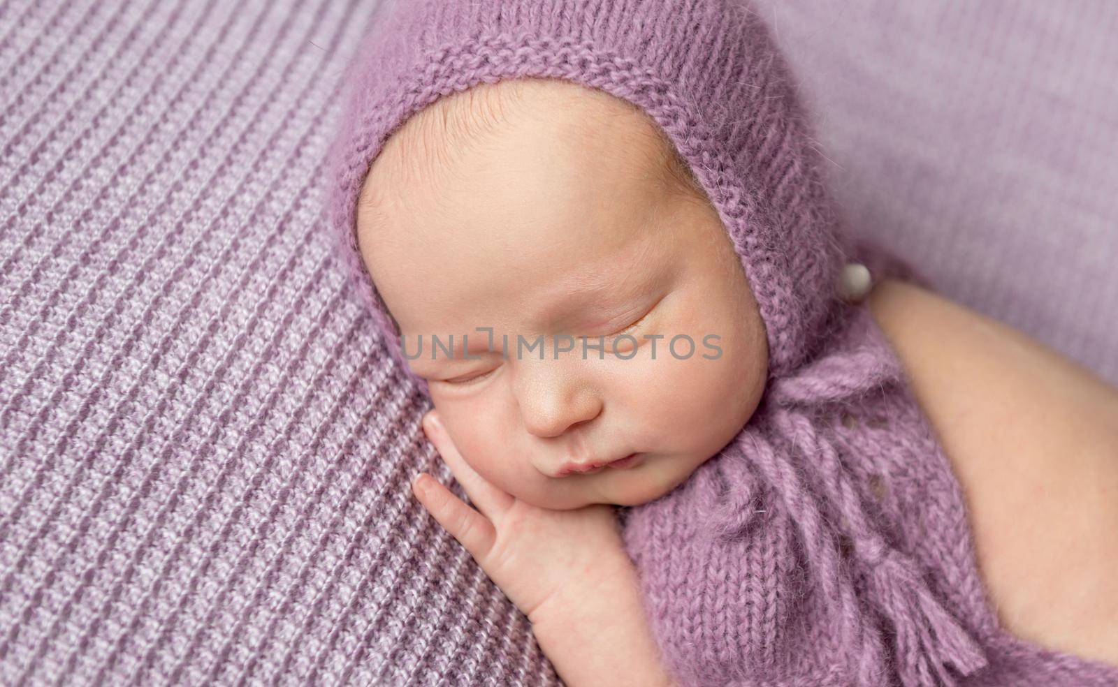 Cute little girl in purple knitted bonnet sleeping on her side by tan4ikk1