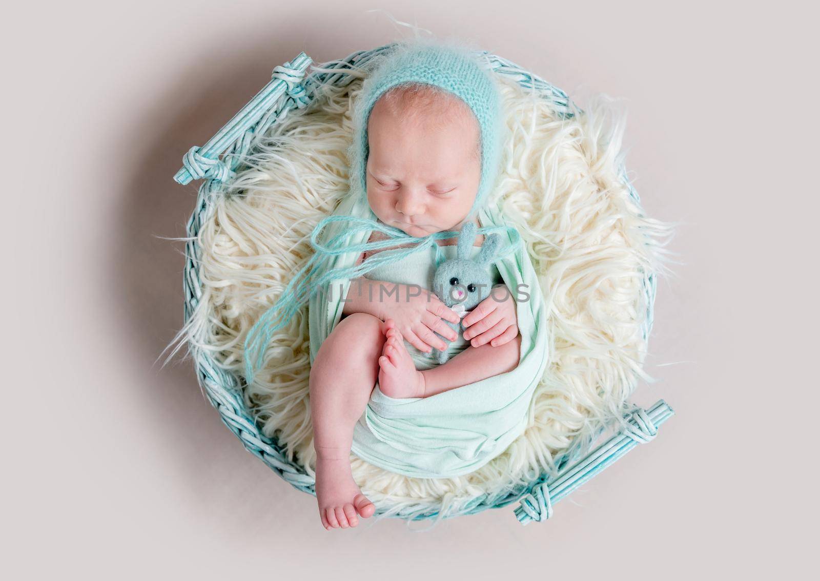 sweet newborn wrapped in a nappy sleeping on a round rug top view