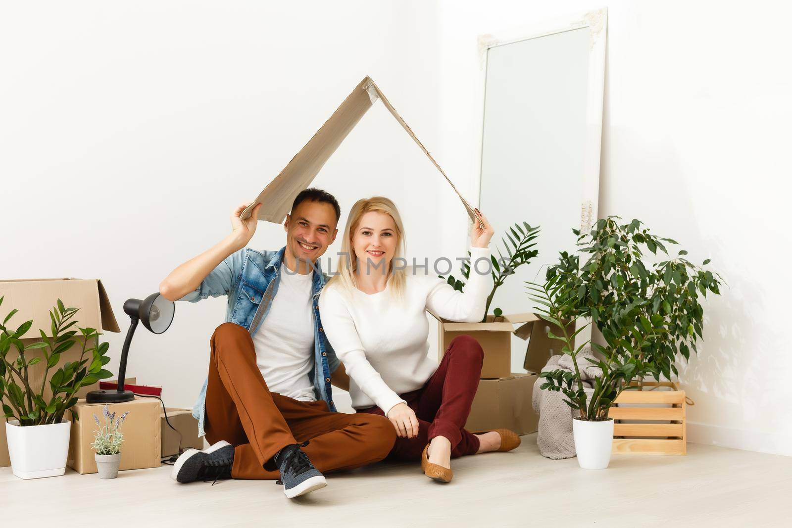 Young couple carrying big cardboard box at new home.Moving house. by Andelov13