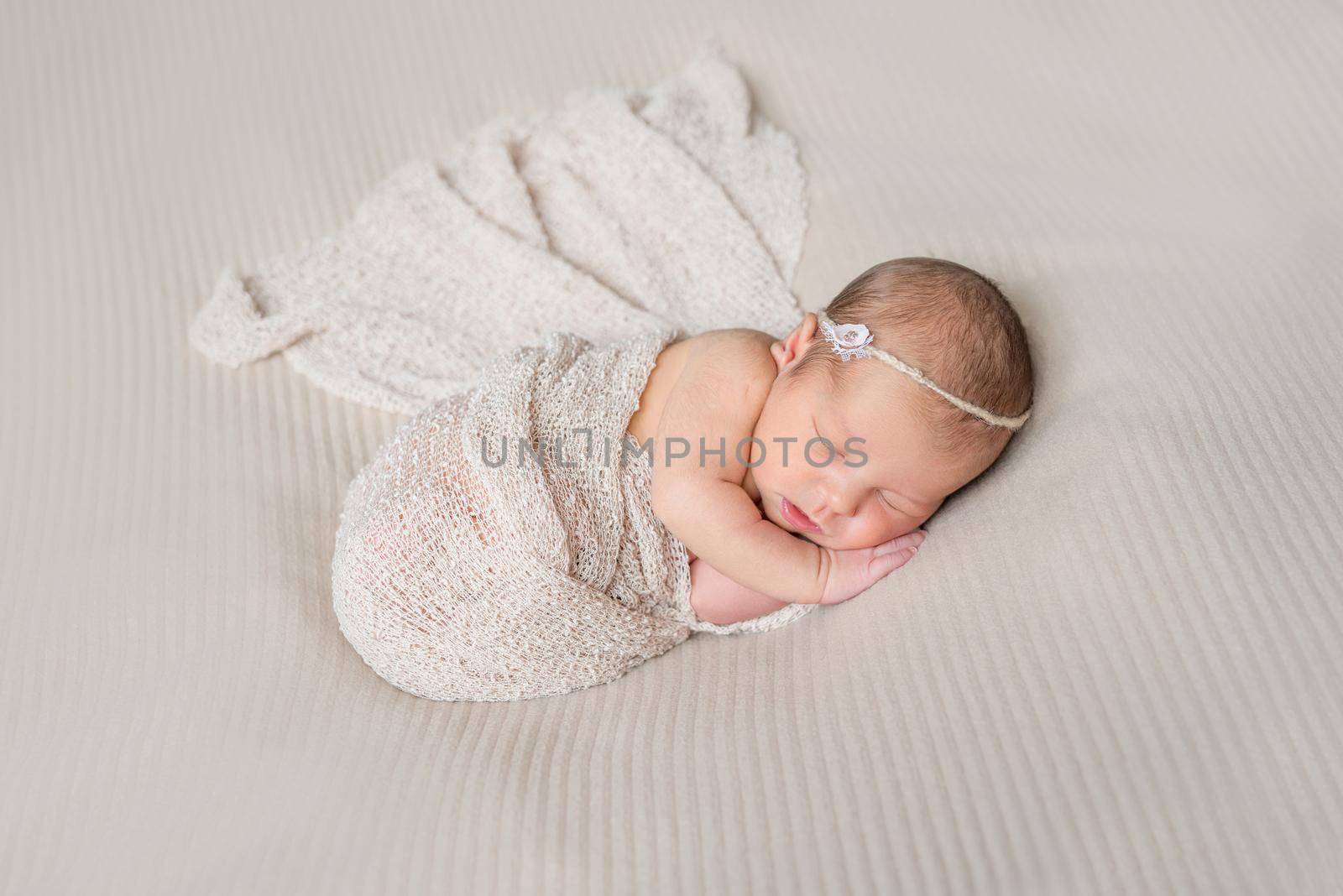 lovely smiling sleeping infant wrapped in gray warm diaper