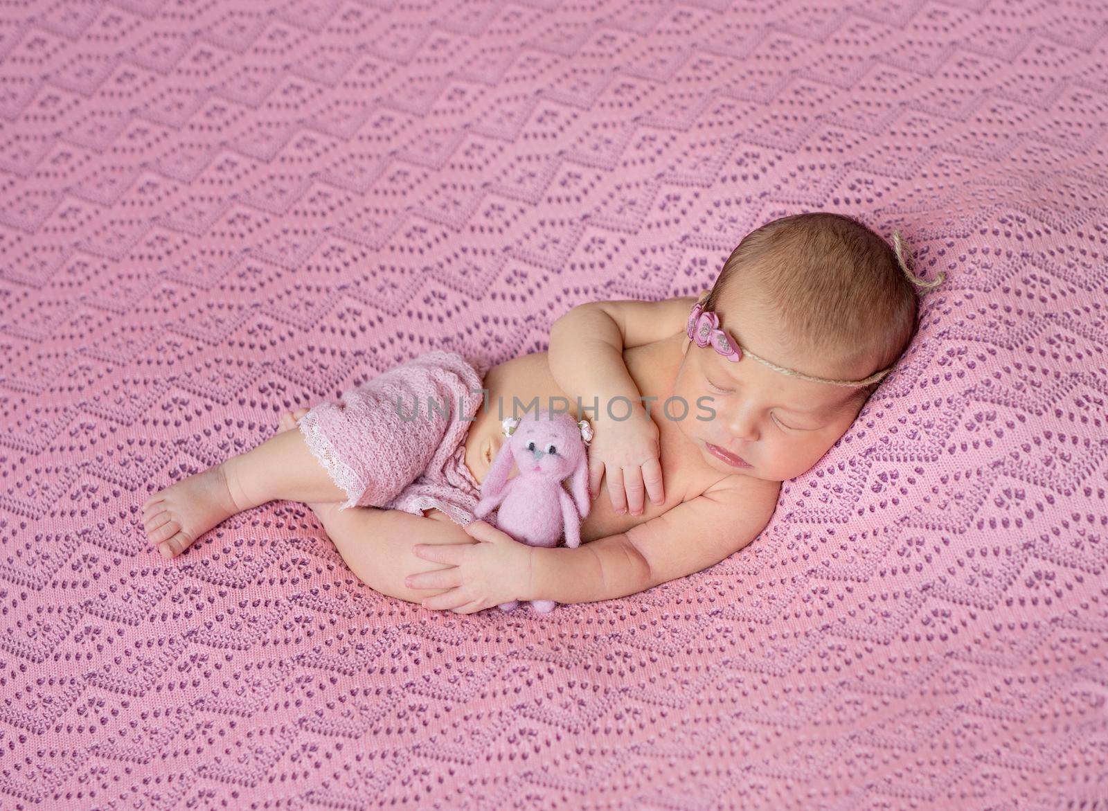 lovely sleeping newborn baby in pink hat and panties on pink blanket