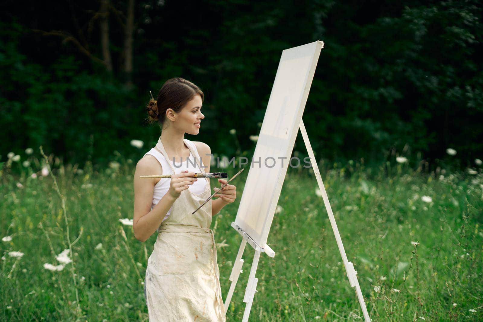 woman artist with palette of paints drawing easel nature hobby. High quality photo