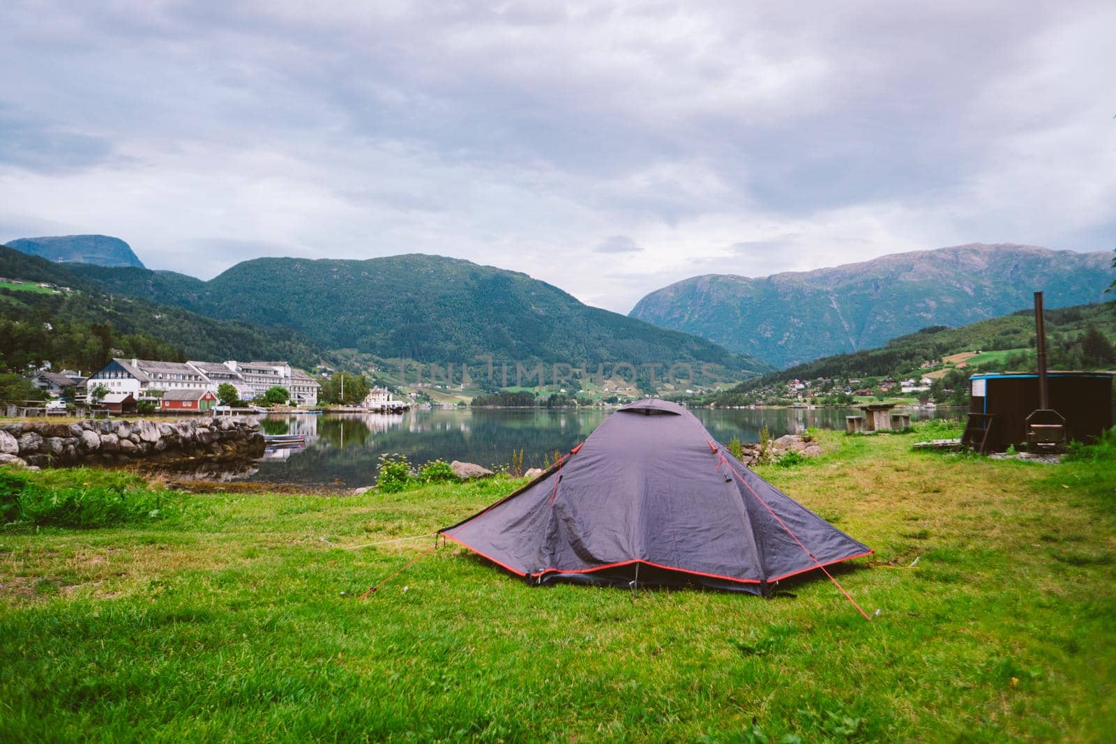 Norwegian fjord landscape with camping tent. Norway adventure. Camping tent at scenic wild fjord, a lake shore with mountain range in background - Norway. by Tomashevska