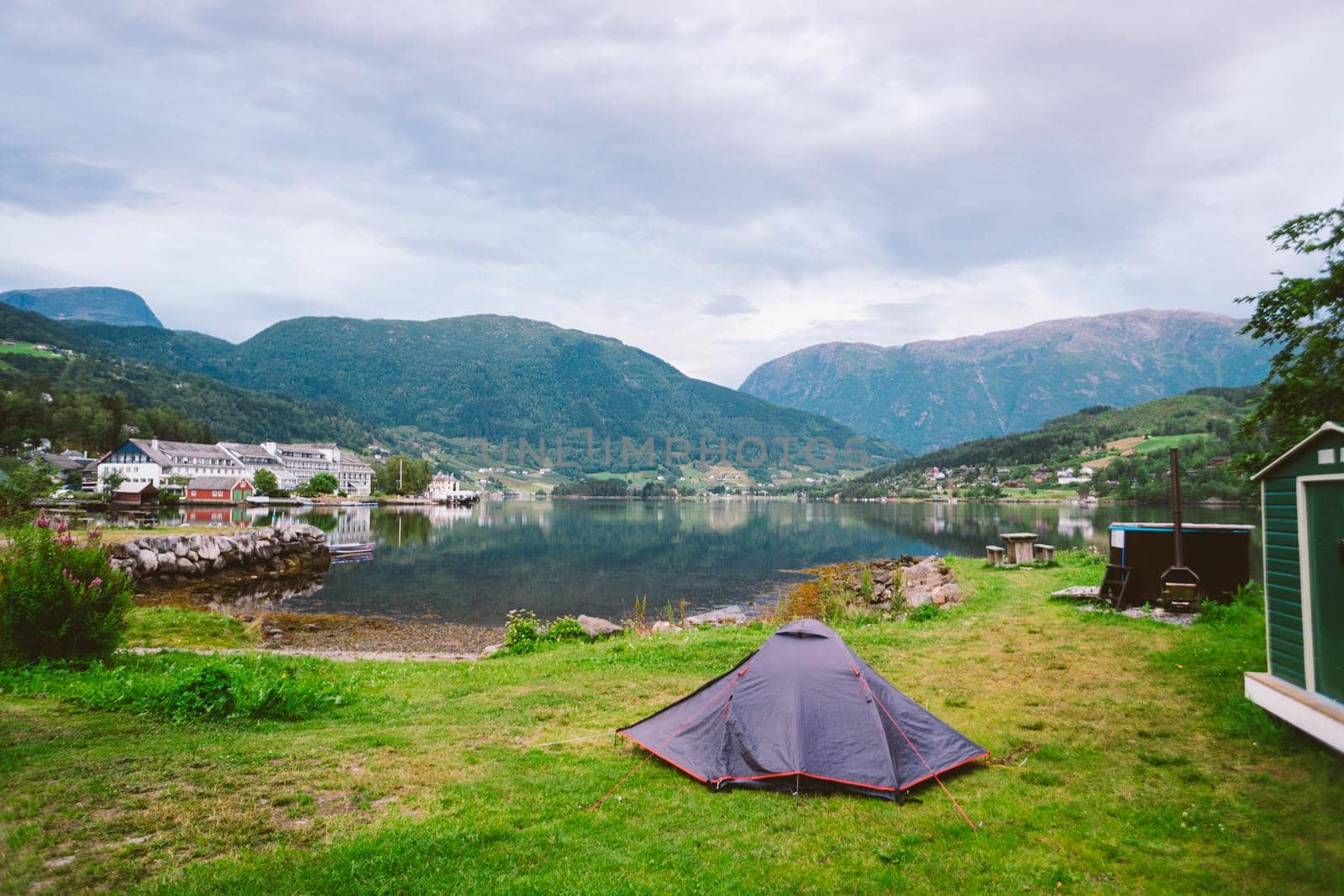 Norwegian fjord landscape with camping tent. Norway adventure. Camping tent at scenic wild fjord, a lake shore with mountain range in background - Norway.