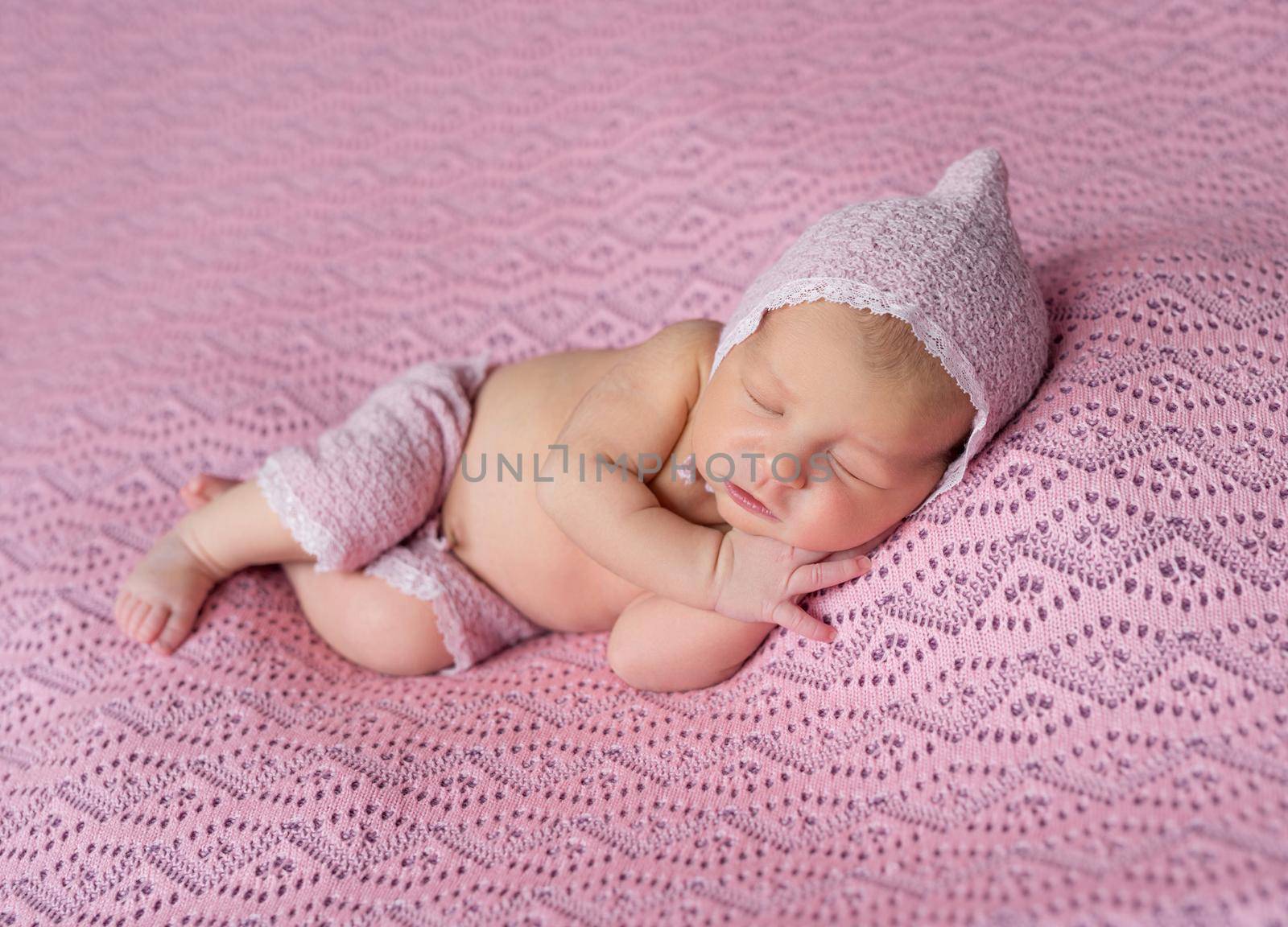 lovely sleeping newborn baby in pink hat and panties on pink blanket