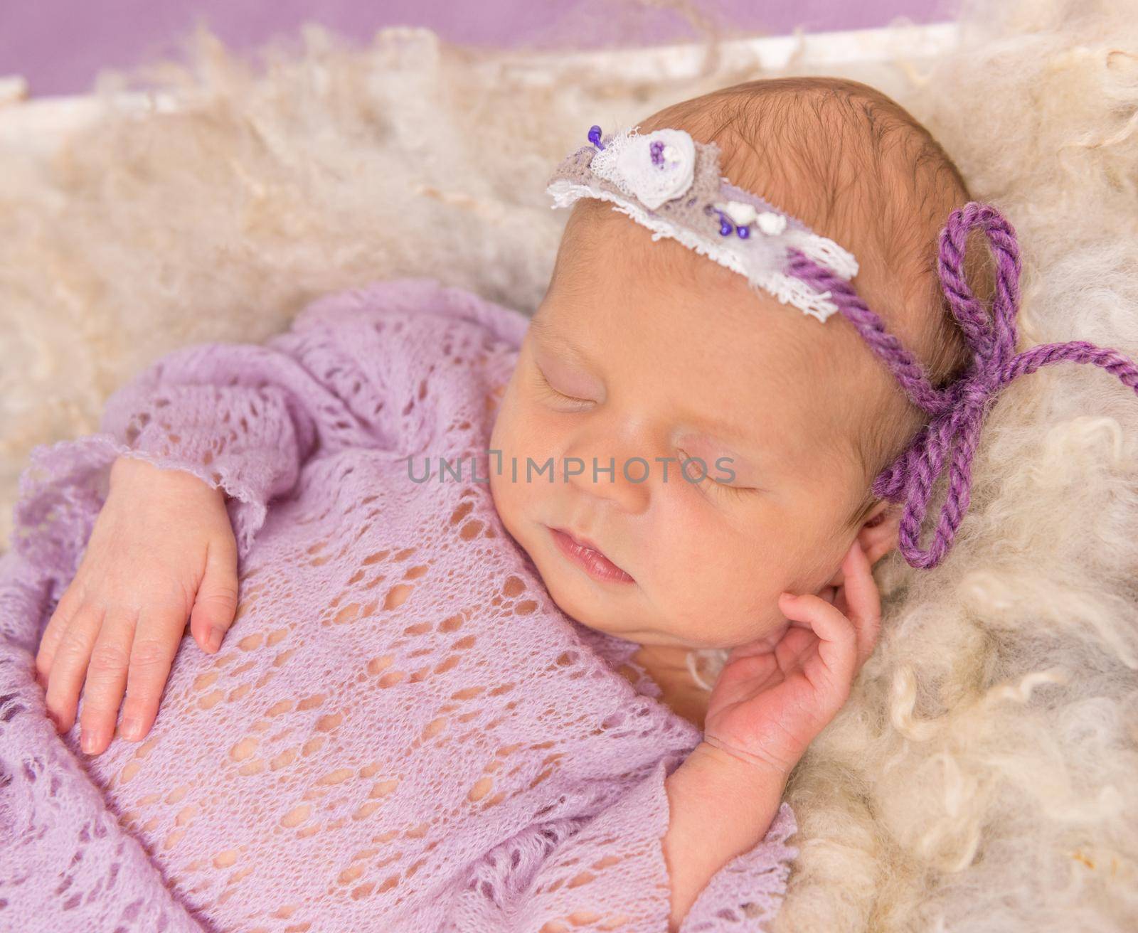 sweet newborn sleeping in square cot on violet background by tan4ikk1