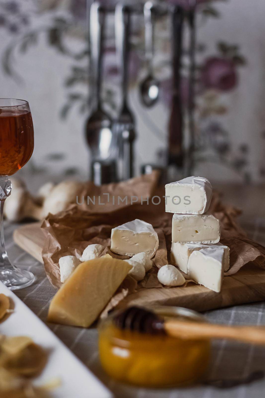 Delicious cheeses on a board with honey and wine on a paper background.