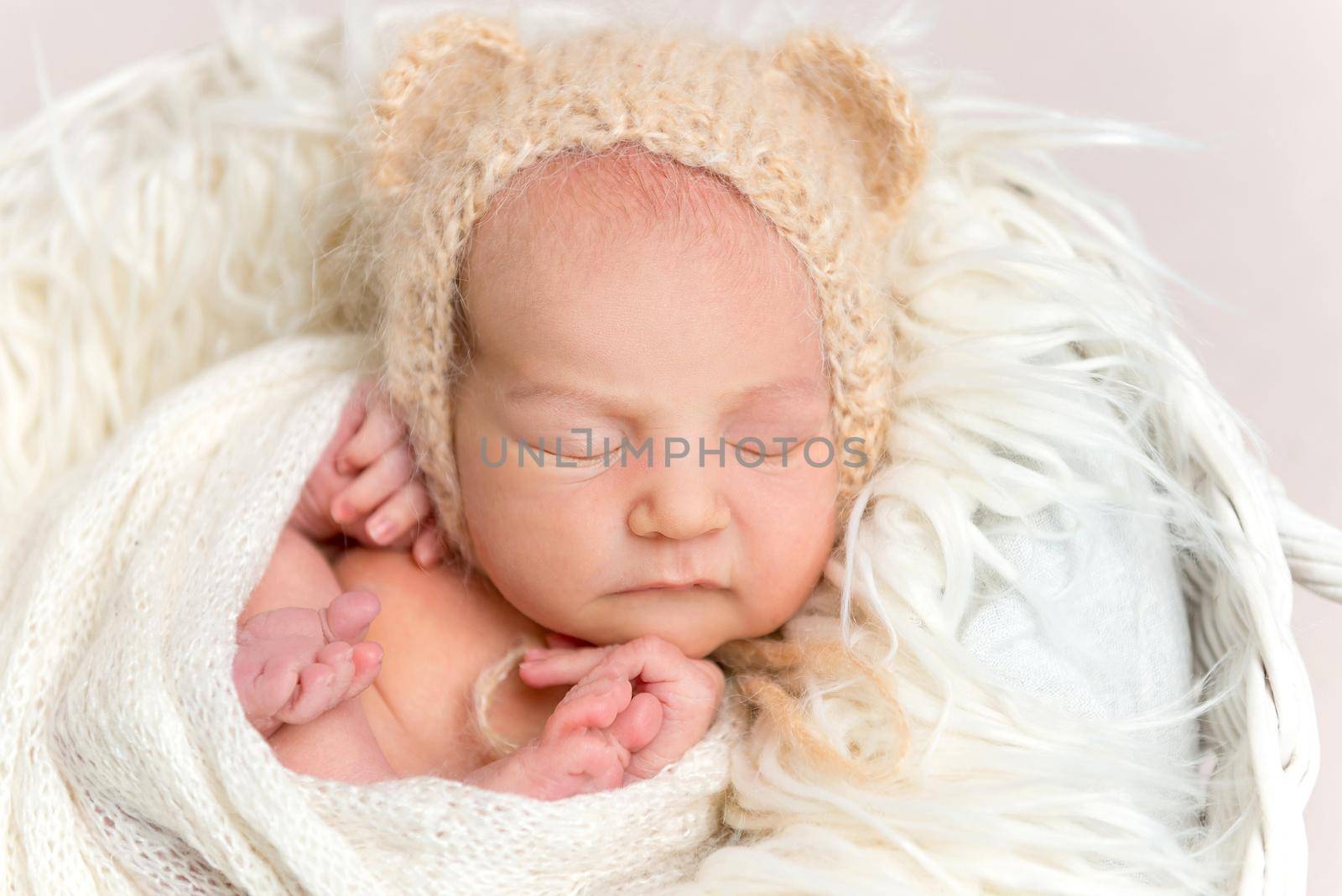 Adorable newborn baby napping in white round basket, top view. Little newborn baby in funny bonnet with ears