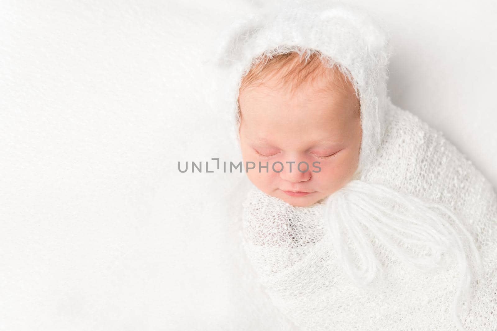 beautiful swaddled newborn baby in white closeup with ears