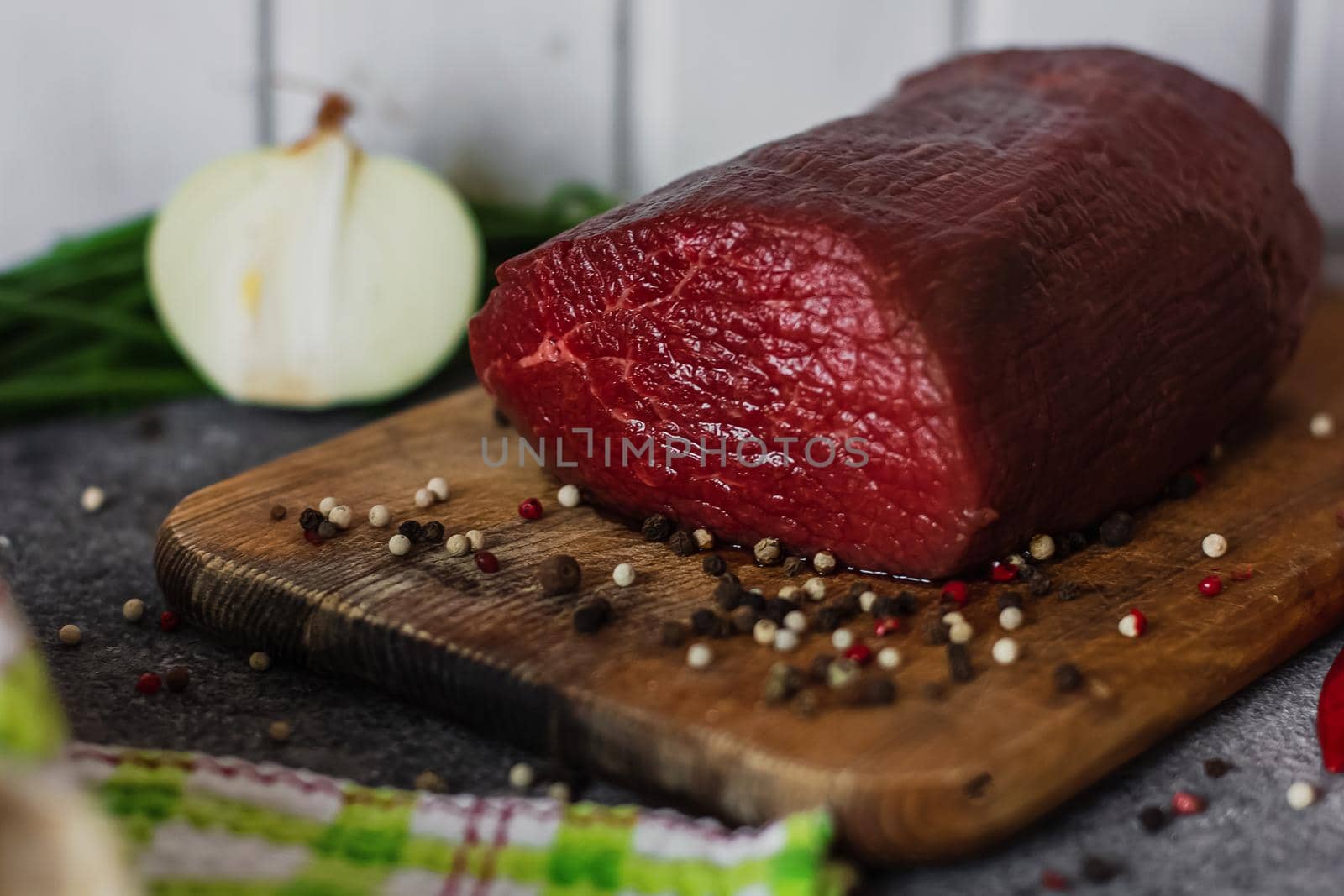 Raw meat. A large piece of beef chop on a wooden cutting board with pepper and spices.