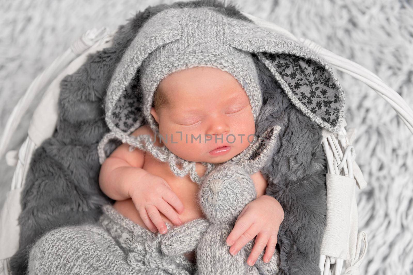 Little baby pressing a rabbit knitted toy to himself while sleeping, closeup